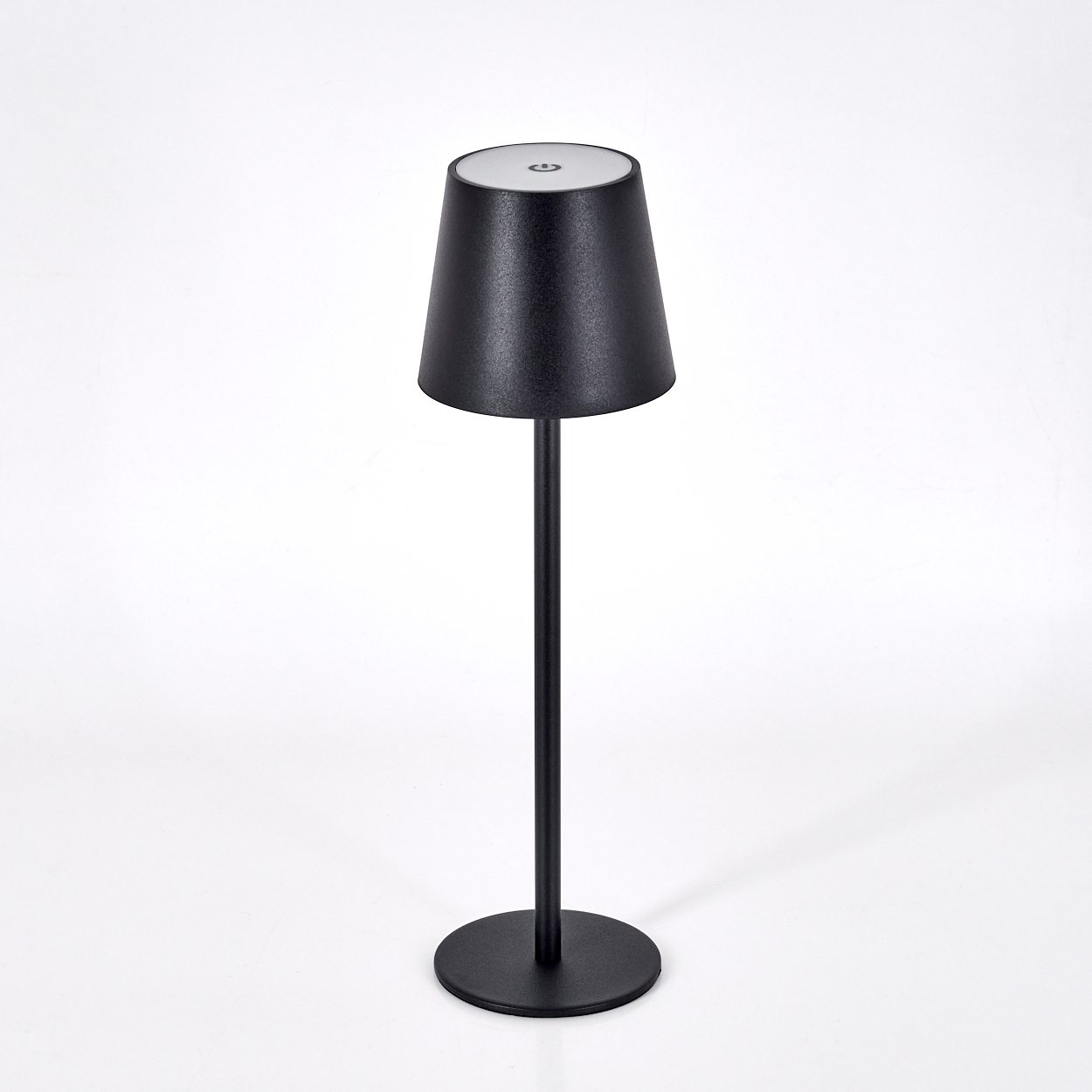 Eine schwarze Lampe mit konischem Schirm steht auf weißem Grund. Die Lampe hat einen runden Sockel und einen schlanken Stiel.