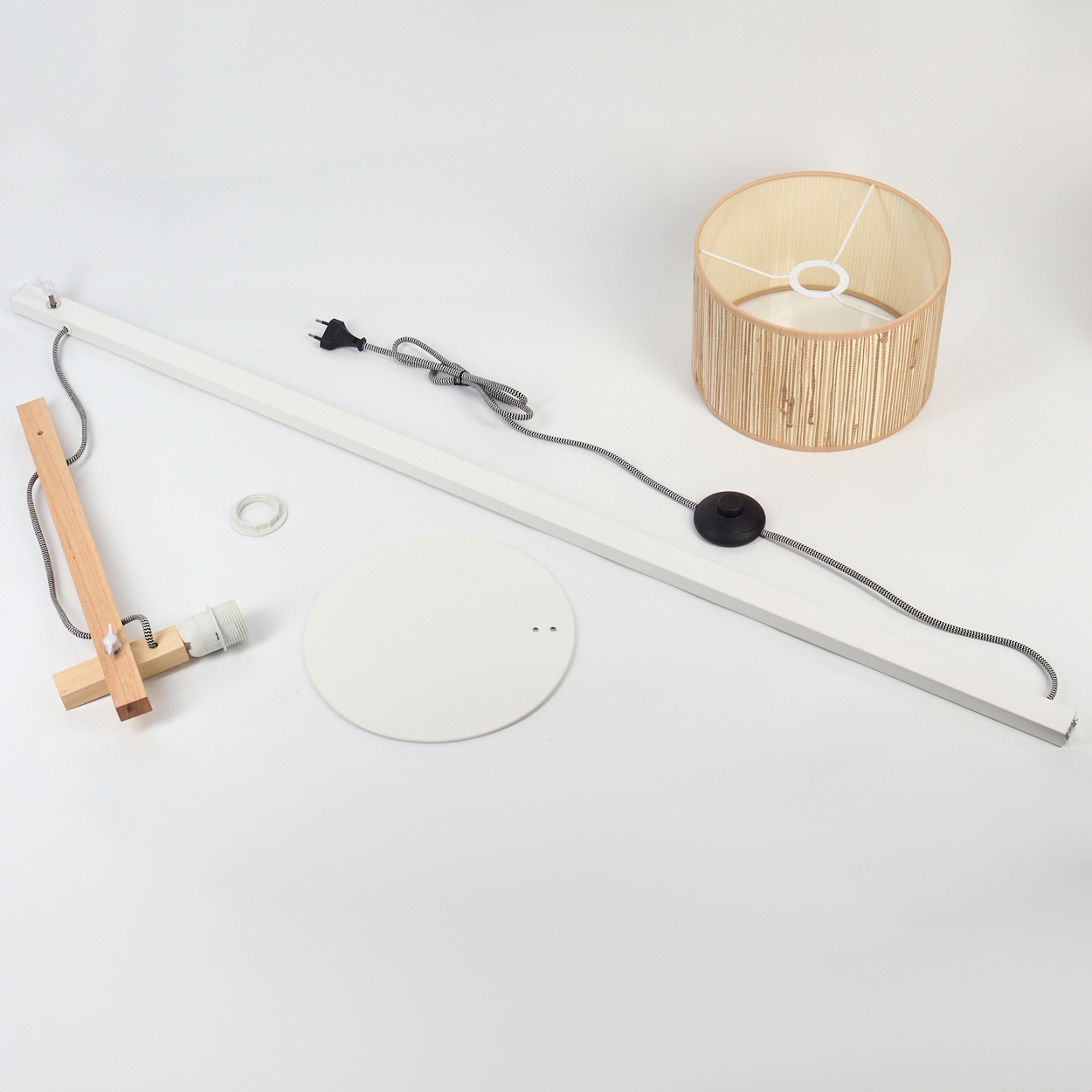 Zerlegte Stehlampe auf Weiß. Enthält Schirm, Sockel, Stiel, Holzträger, Glühbirnenhalter und Verkabelung. Komponenten sind getrennt.