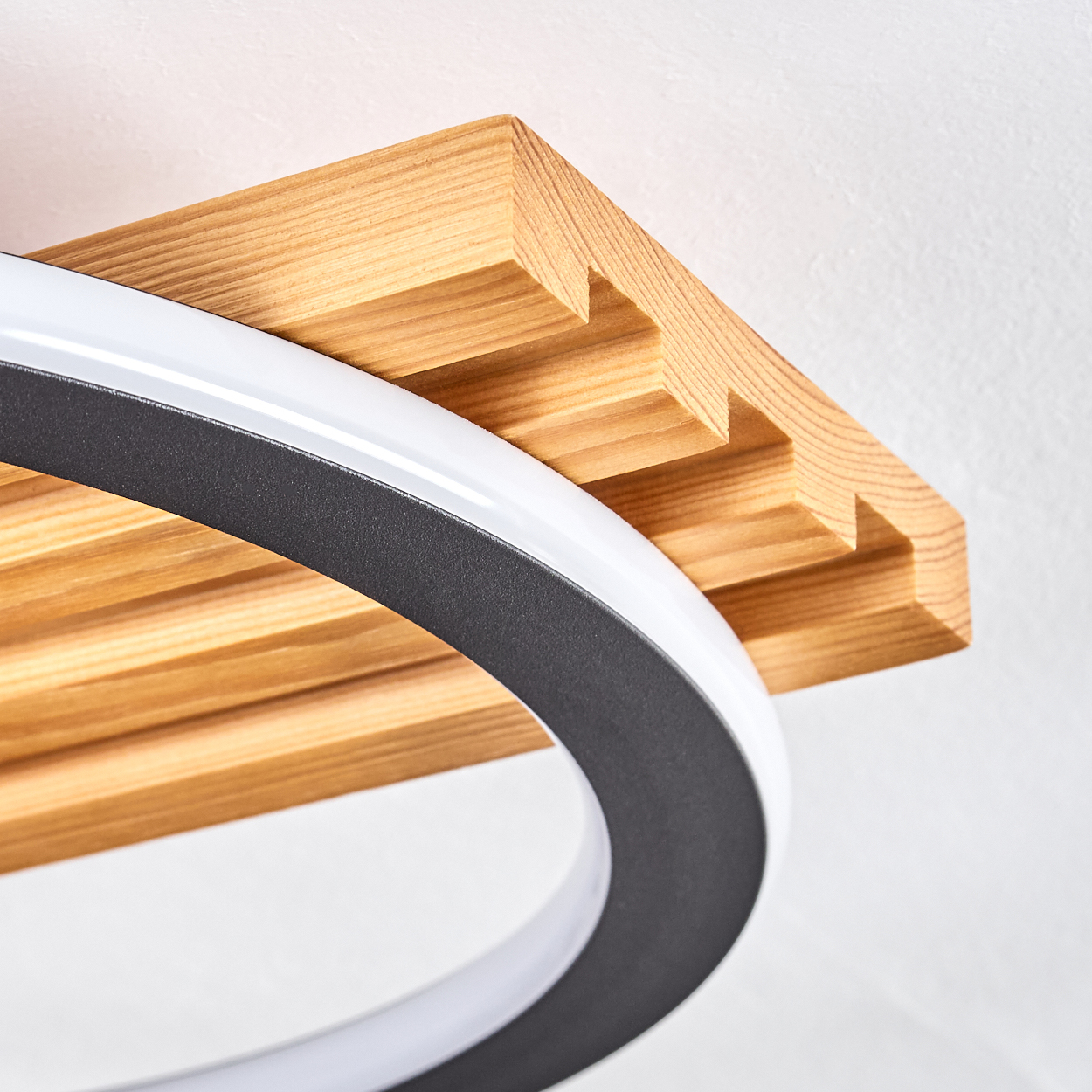 Ein Holzbalken mit einer schwarz-weißen kreisförmigen Leuchte. Das Holz ist hellbraun und die Leuchte befindet sich im Vordergrund.