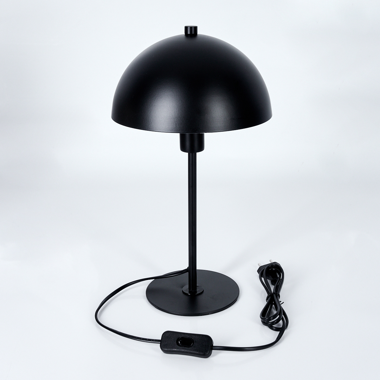Eine schwarze Schreibtischlampe mit Kuppel, geradem Ständer und rundem Fuß. Sie hat einen Schalter und ein Netzkabel auf weißem Hintergrund.