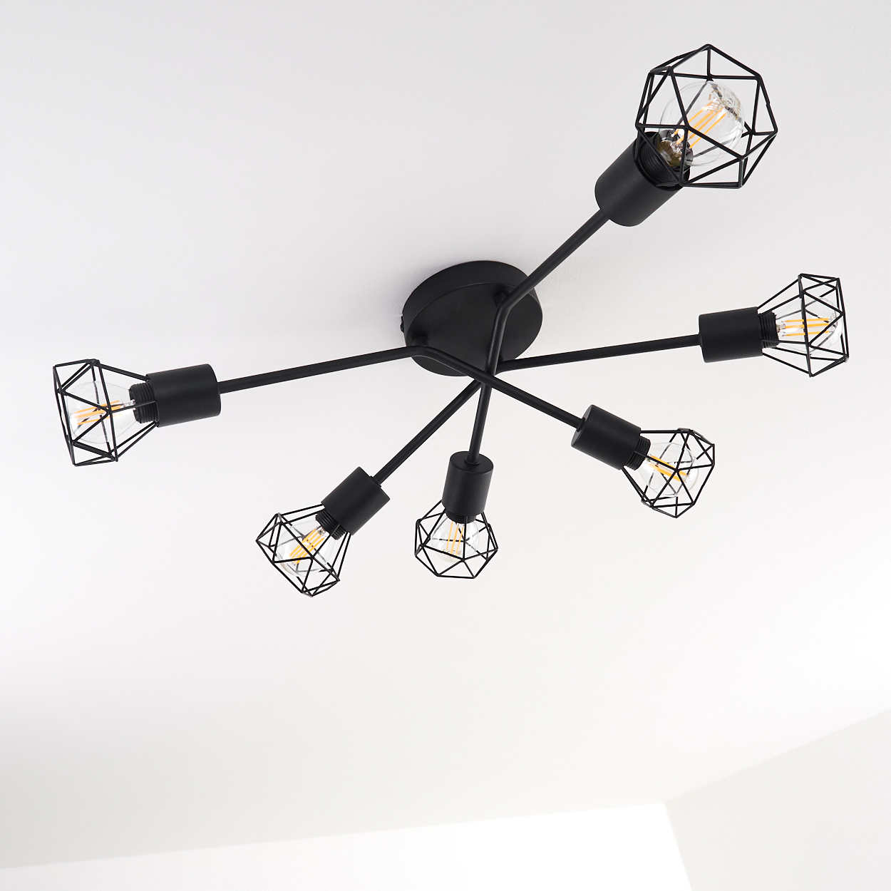 Schwarze Deckenleuchte mit sechs Glühbirnen. Jede Glühbirne ist in einem geometrischen Drahtrahmen eingeschlossen.