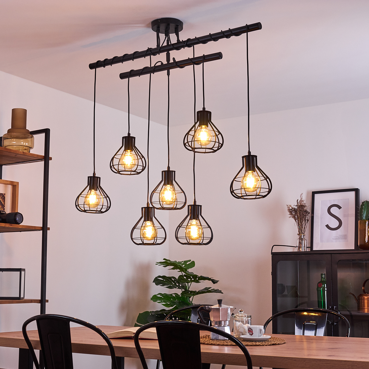 Ein modernes Esszimmer mit Holztisch, schwarzen Stühlen und einem stilvollen schwarzen Kronleuchter mit sieben käfigartigen Lichtern.