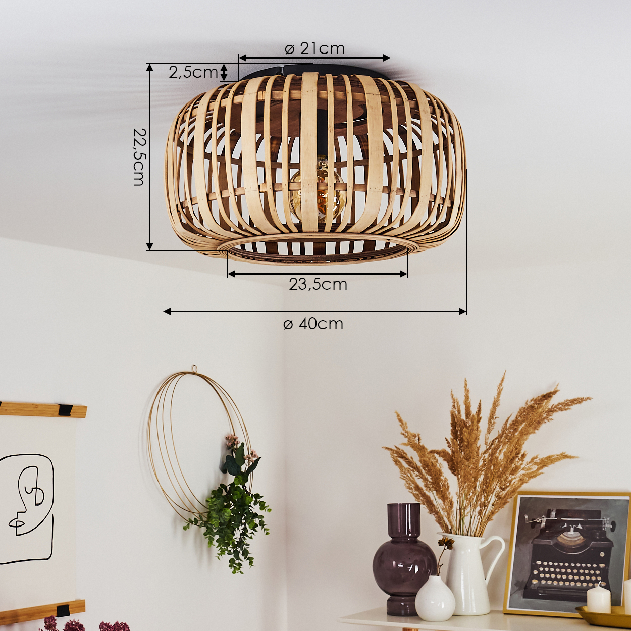 Eine Bambuslampe hängt von der Decke. Darunter ist eine Wand mit einem Kranz und Kunstwerken dekoriert. Ein Regal enthält Vasen und ein gerahmtes Bild.