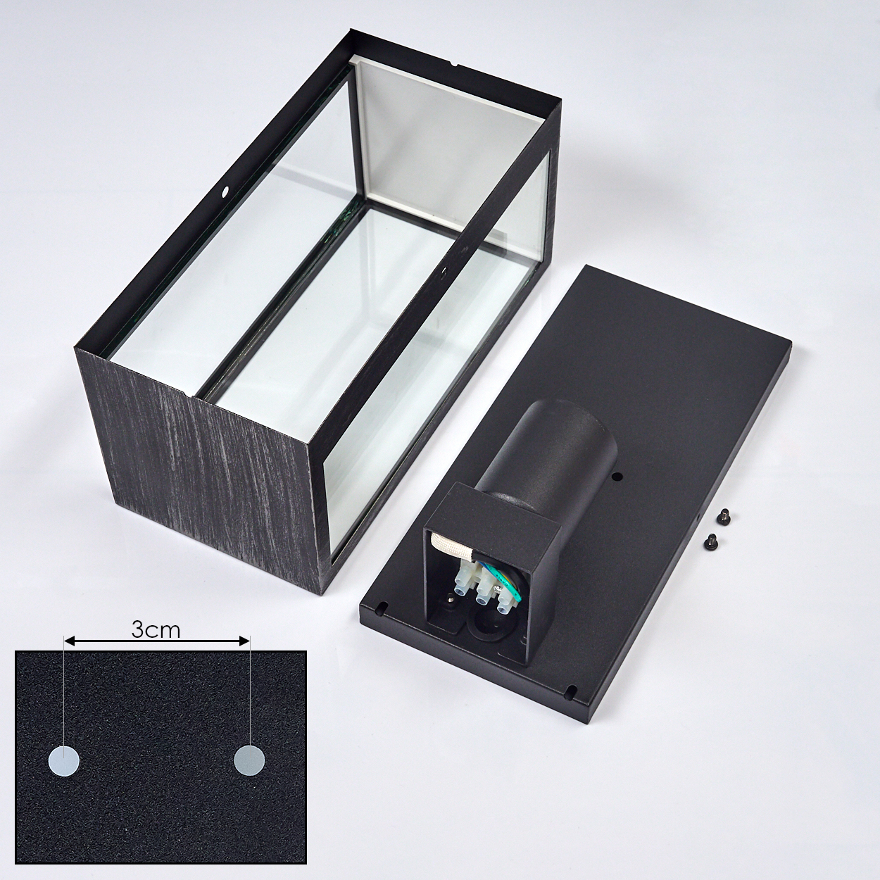 Eine zerlegte rechteckige Lampe. Der Hauptkörper ist schwarz mit Glasscheiben, mit einer separaten schwarzen Basis und elektrischen Komponenten.