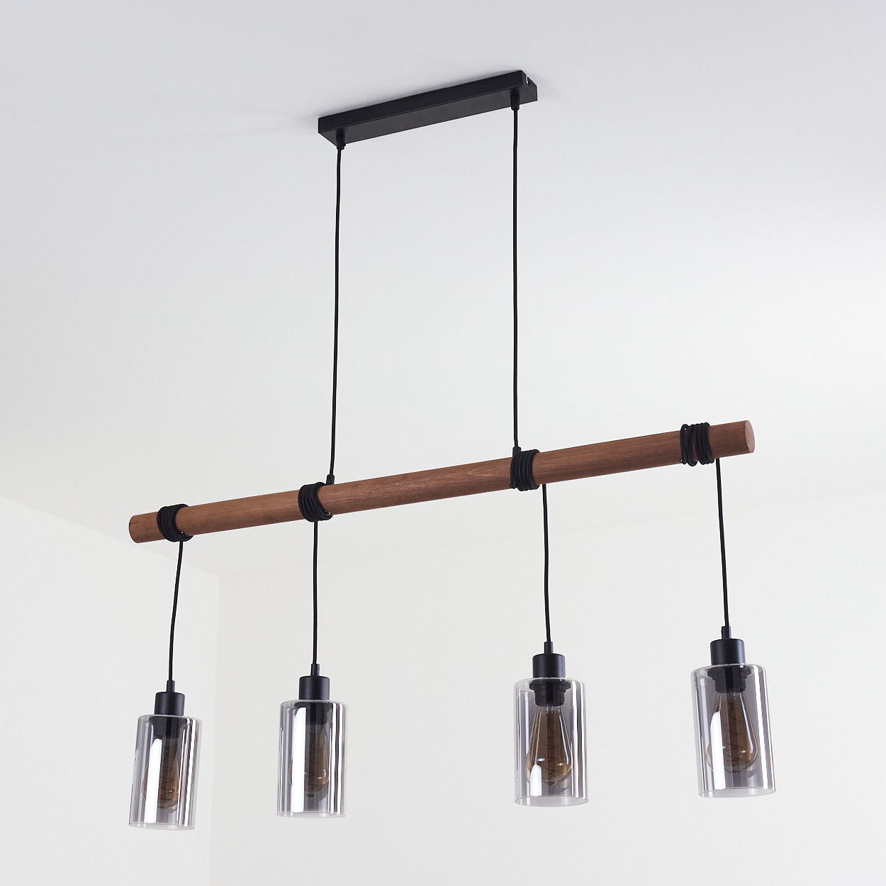 Ein Holzbalken mit vier Hängelampen. Die Lampen haben Glasschirme und schwarze Kabel. Die Decke ist weiß.
