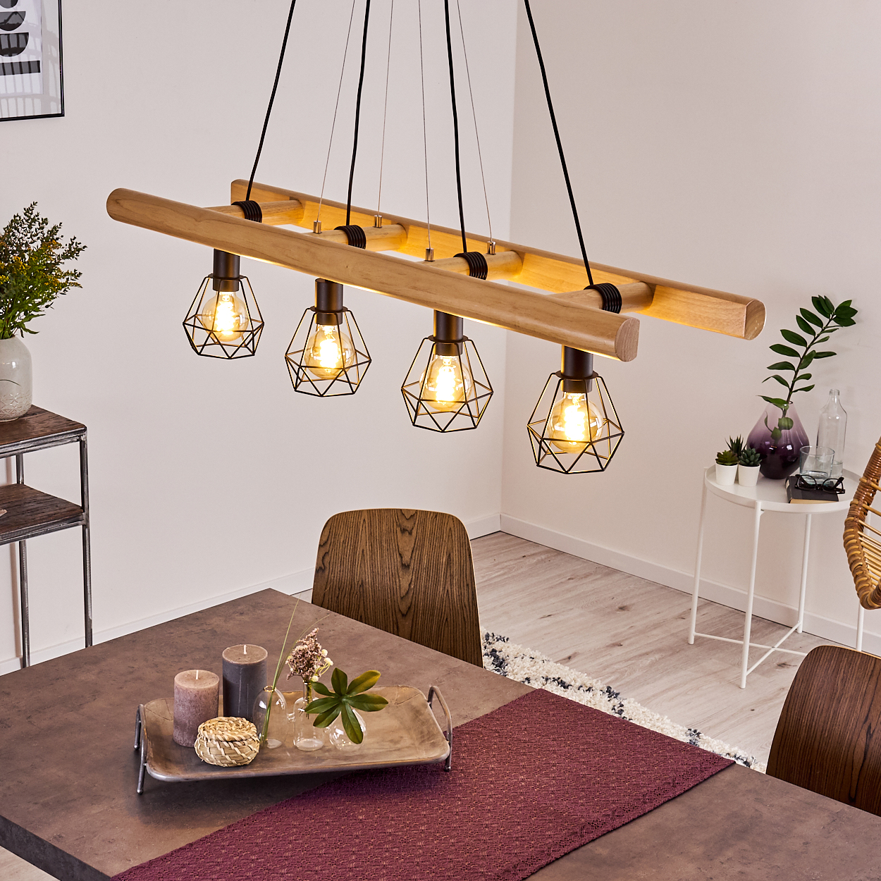 Ein Esszimmer mit Holztisch, Stühlen und einer Hängeleuchte mit vier geometrischen Lampen. Ein Tablett mit Kerzen und Pflanzen.
