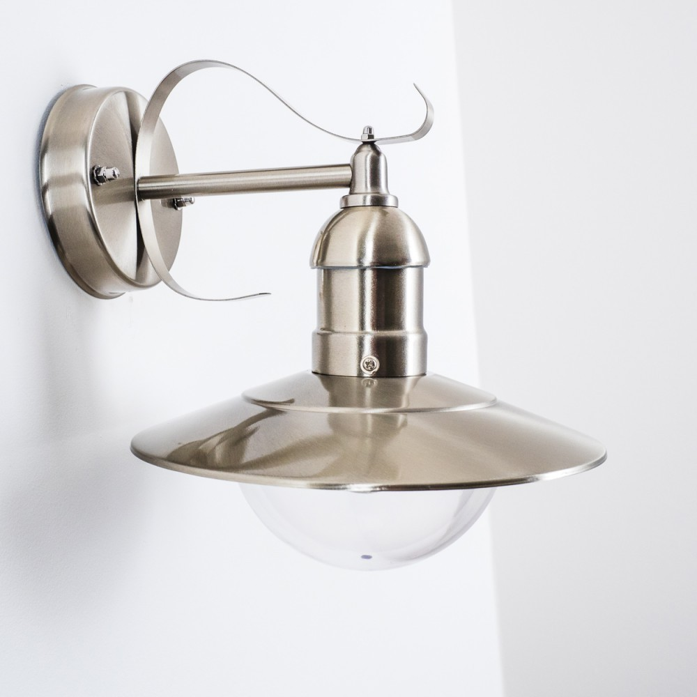 Eine Wandlampe aus gebürstetem Metall mit gebogenem Arm und rundem Schirm. Der Hintergrund ist eine weiße Wand.