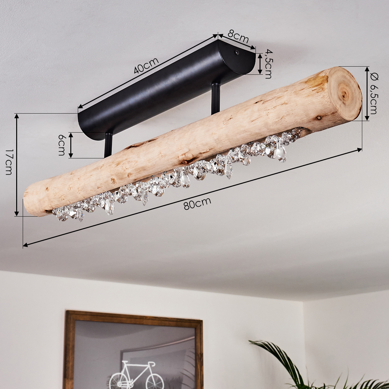 Eine Holz-Deckenleuchte hängt von der Decke. Sie hat eine schwarze Metallhalterung und ist mit Kristallanhängern verziert.
