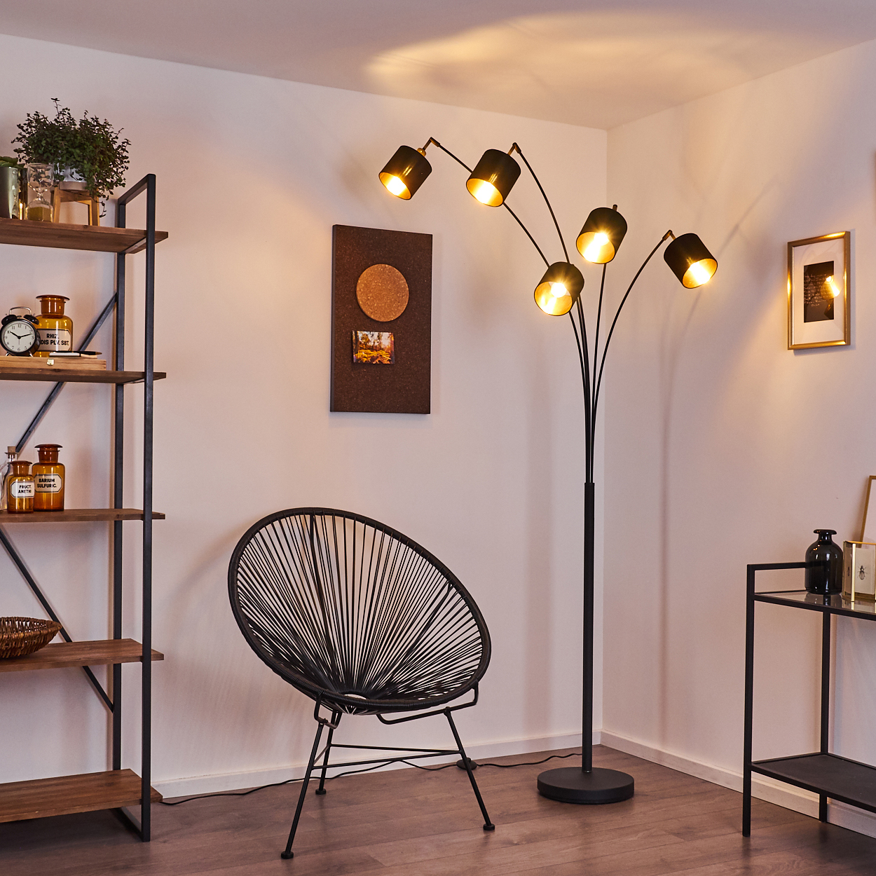 Ein modernes Zimmer mit einer schwarzen Stehlampe, einem schwarzen Stuhl, einem Holzregal und einer Pinnwand. Warme Beleuchtung schafft eine gemütliche Atmosphäre.