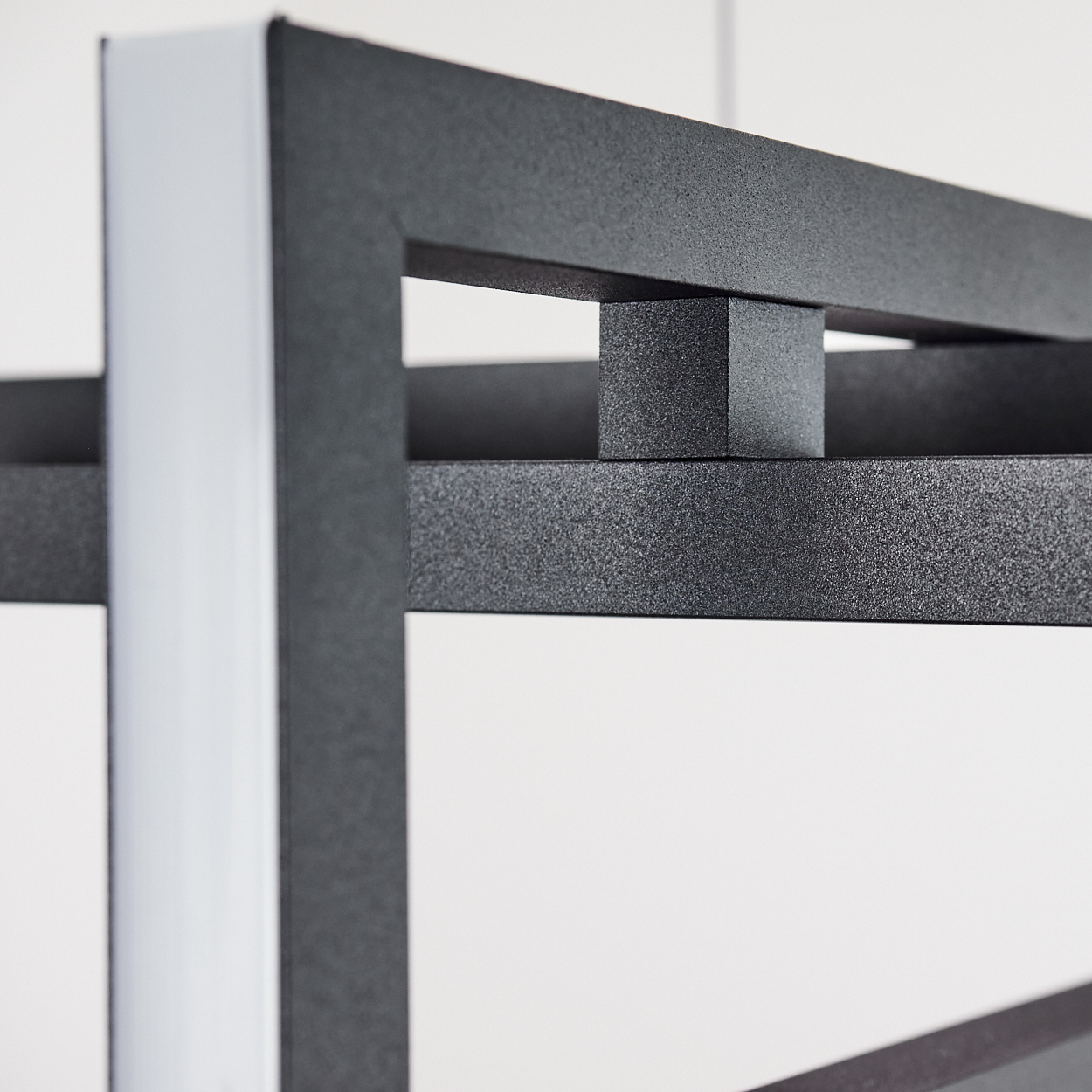 Nahaufnahme einer Metallkonstruktion. Die Struktur ist grau und hat eine rechteckige Form. Auf der linken Seite befindet sich ein weißes vertikales Element.