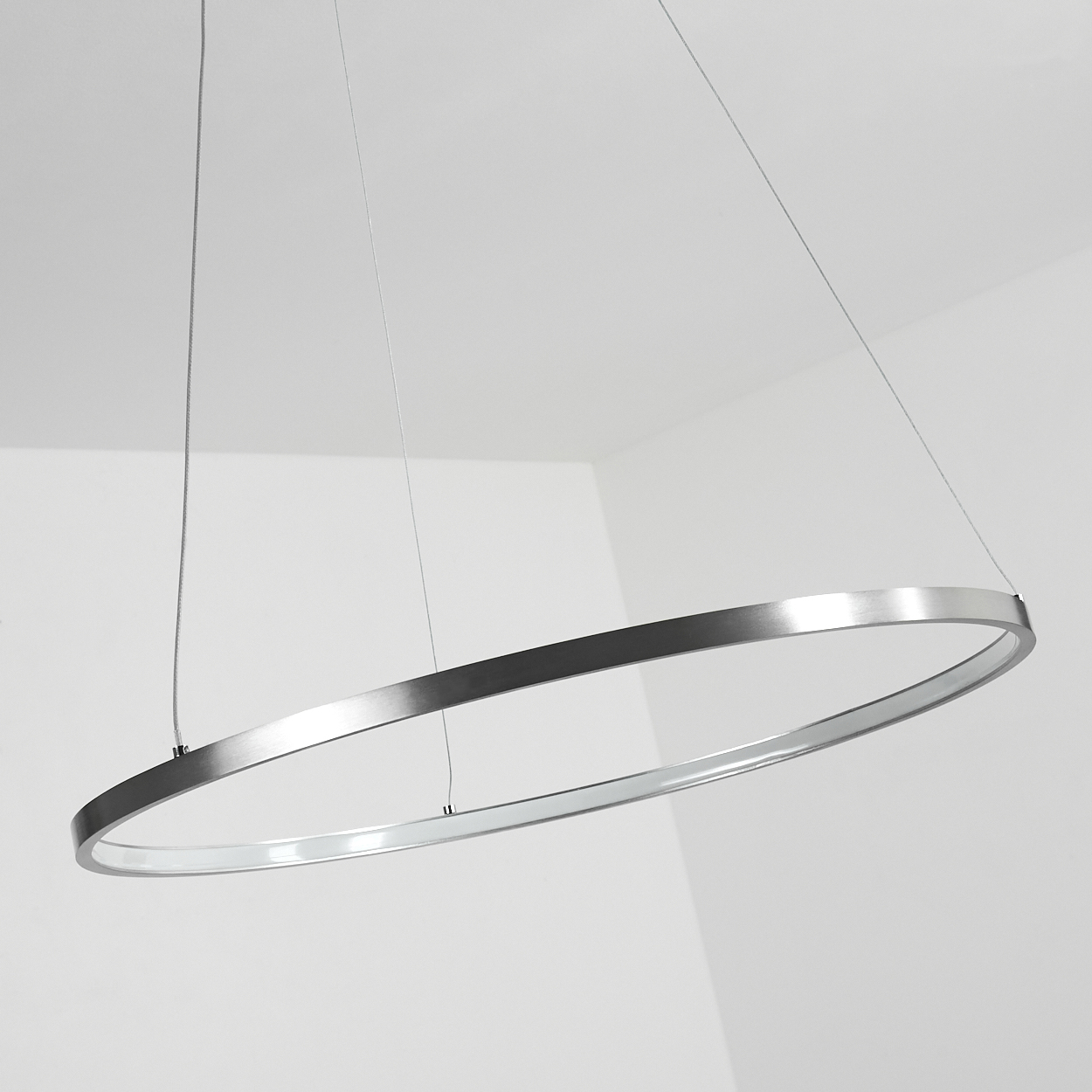 Eine moderne, silberfarbene, ringförmige Leuchte hängt von der Decke. Der Hintergrund ist eine weiße Wand.