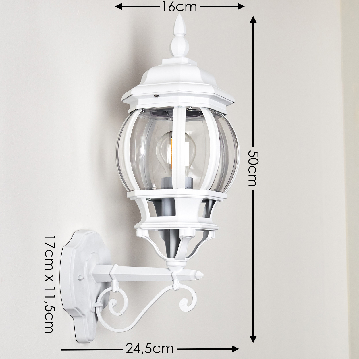 Weiße Außenlampe mit Glaskugel, Abmessungen angegeben. Sie ist an einer weißen Wand montiert. Die Lampe hat einen dekorativen Arm.