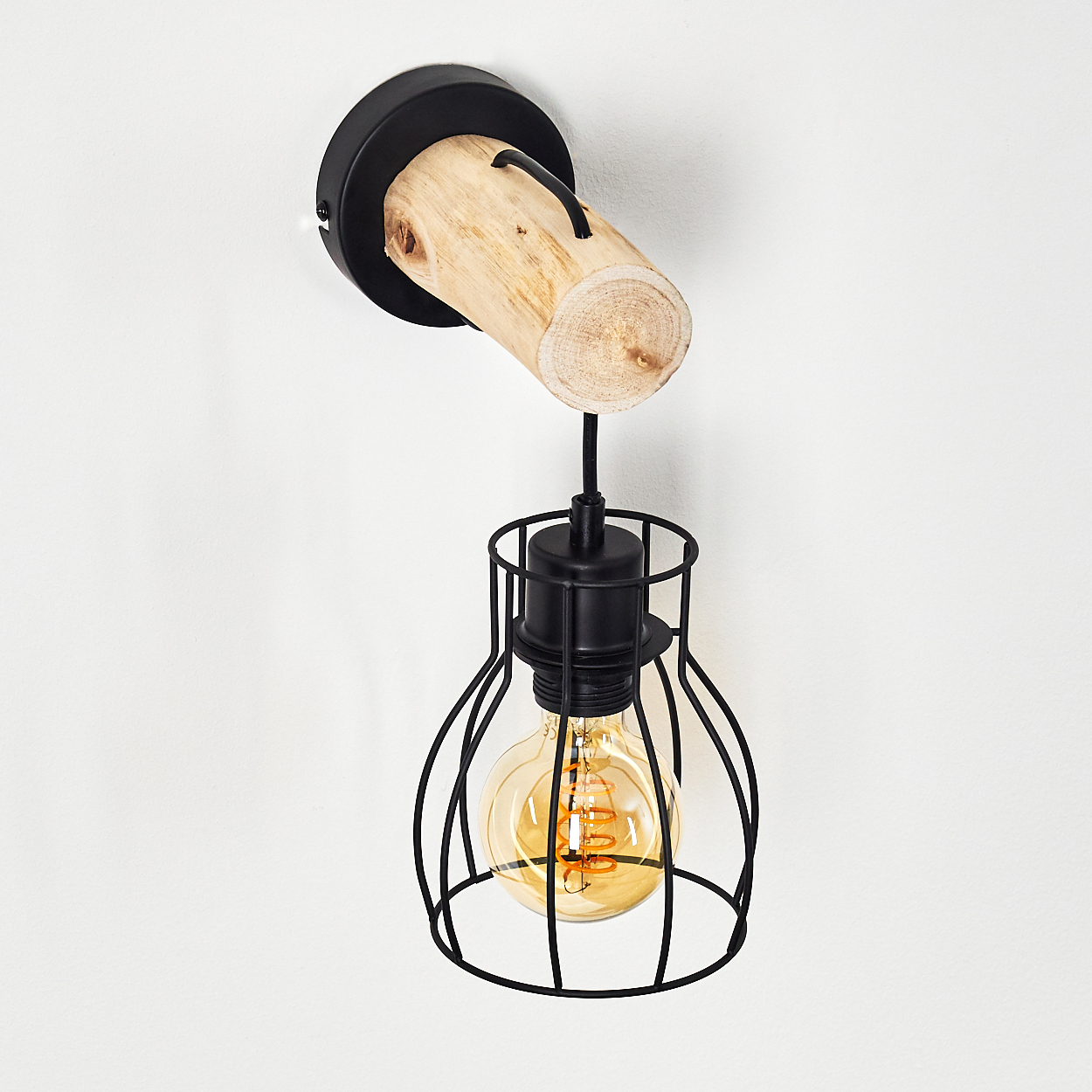 Eine Wandleuchte mit Holzbalken und schwarzem Metallkäfig. Die Lampe hat eine Glühbirne und befindet sich an einer weißen Wand.