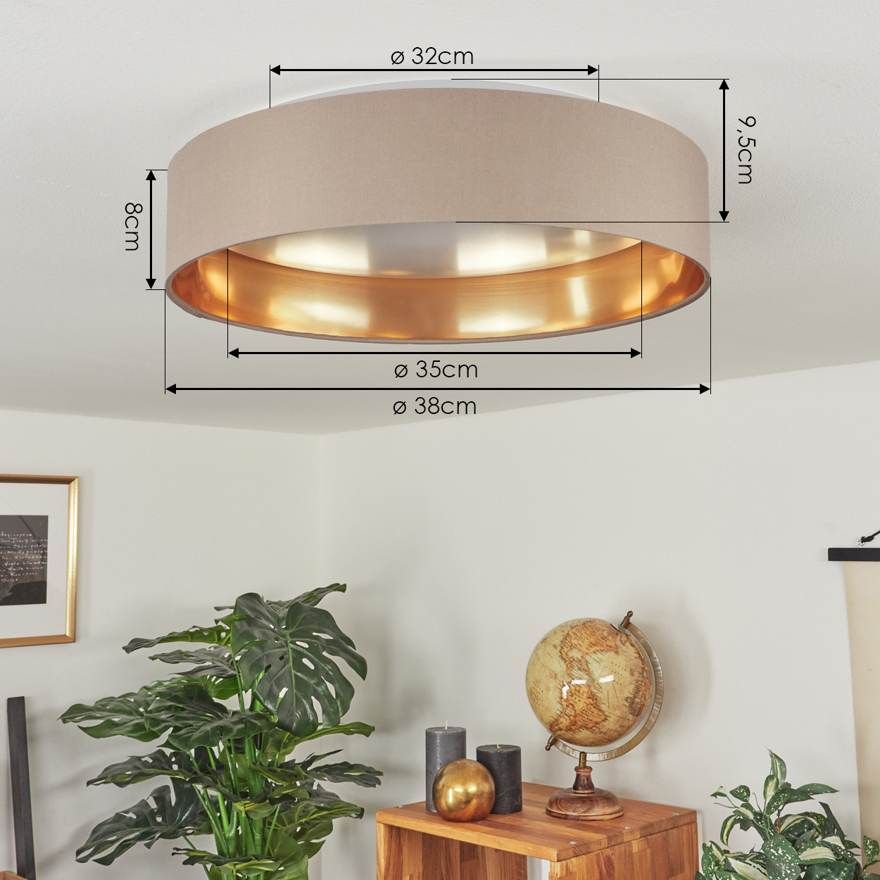 Eine beige Deckenleuchte mit goldenem Innenraum ist an einer weißen Decke befestigt. Ein Holztisch hat einen Globus, Kerzen und Pflanzen.