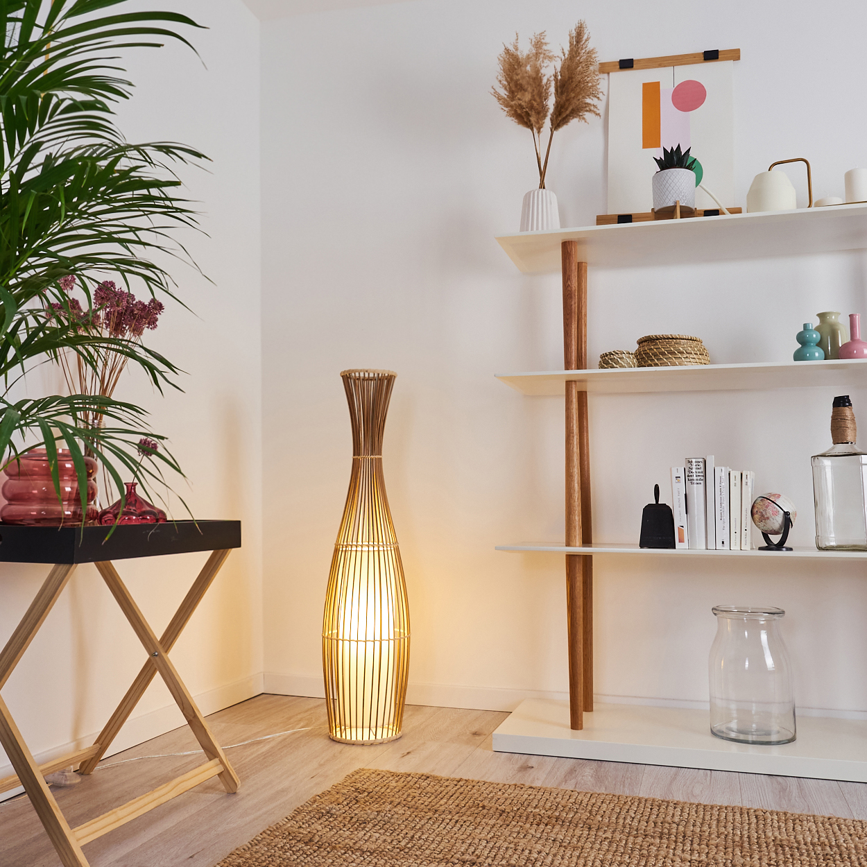Ein Raum mit Stehlampe, Regalen mit Dekor, einem Tabletttisch mit Pflanzen und einem Teppich auf dem Holzboden.