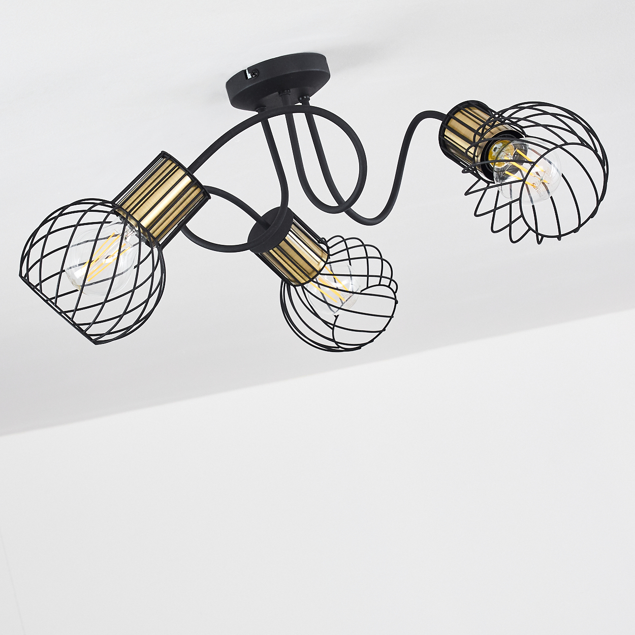 Deckenleuchte mit drei schwarzen Lampen mit Drahtkäfig. Jede hat einen goldfarbenen Sockel und eine sichtbare Glühbirne, die an der Decke befestigt ist.