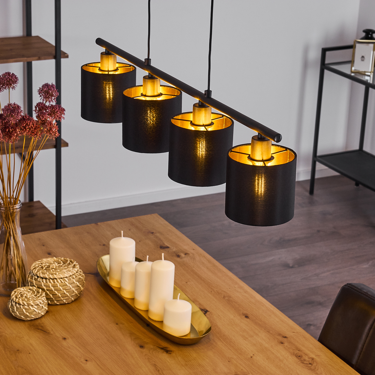 Ein Esszimmer mit Holztisch, schwarzen Lampen, Kerzen und einer Blumenvase. Im Hintergrund steht ein Stuhl.