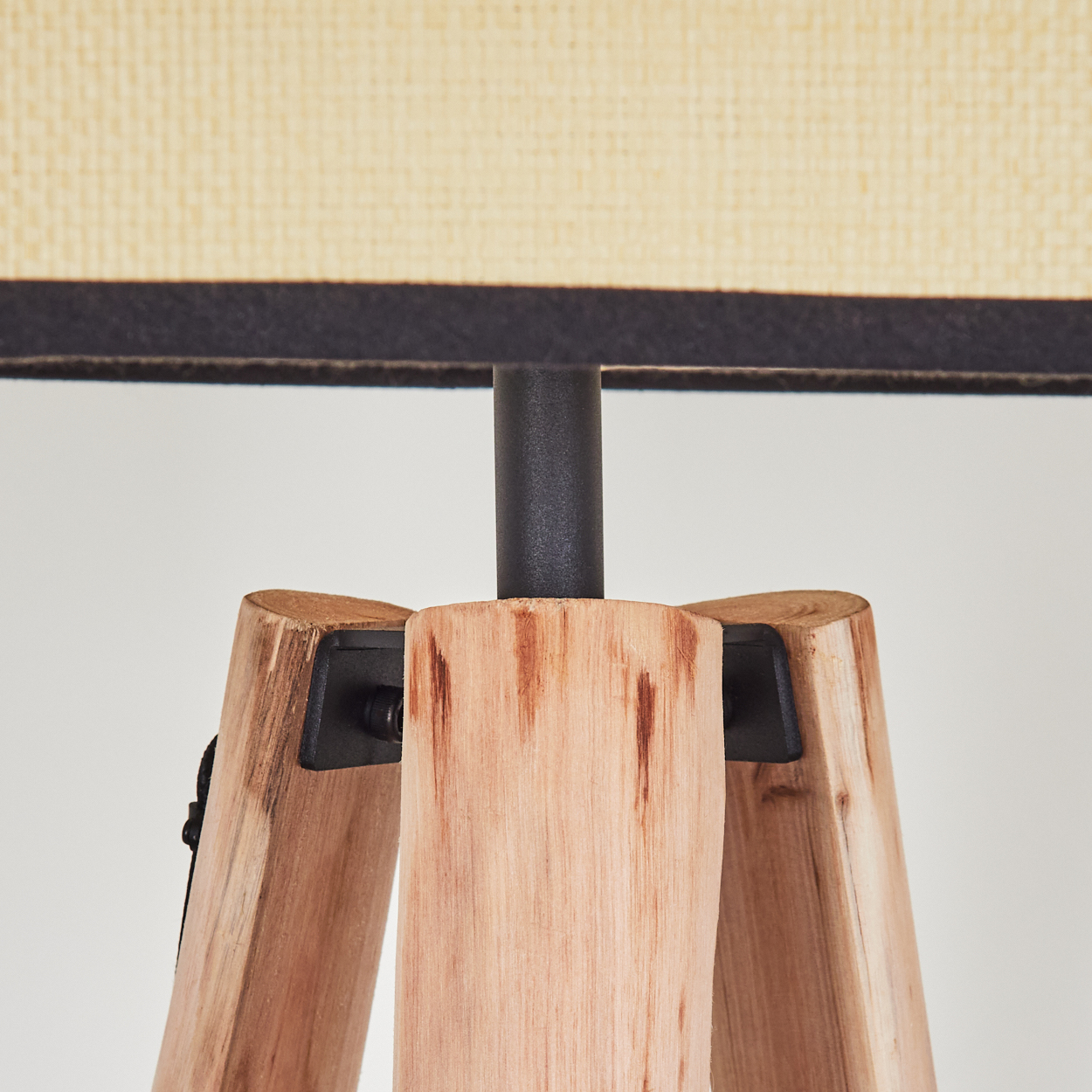Nahaufnahme eines Lampenfußes aus Holz mit beigem Lampenschirm. Der Fuß ist aus hellem Holz gefertigt, der Schirm ist cremefarben.