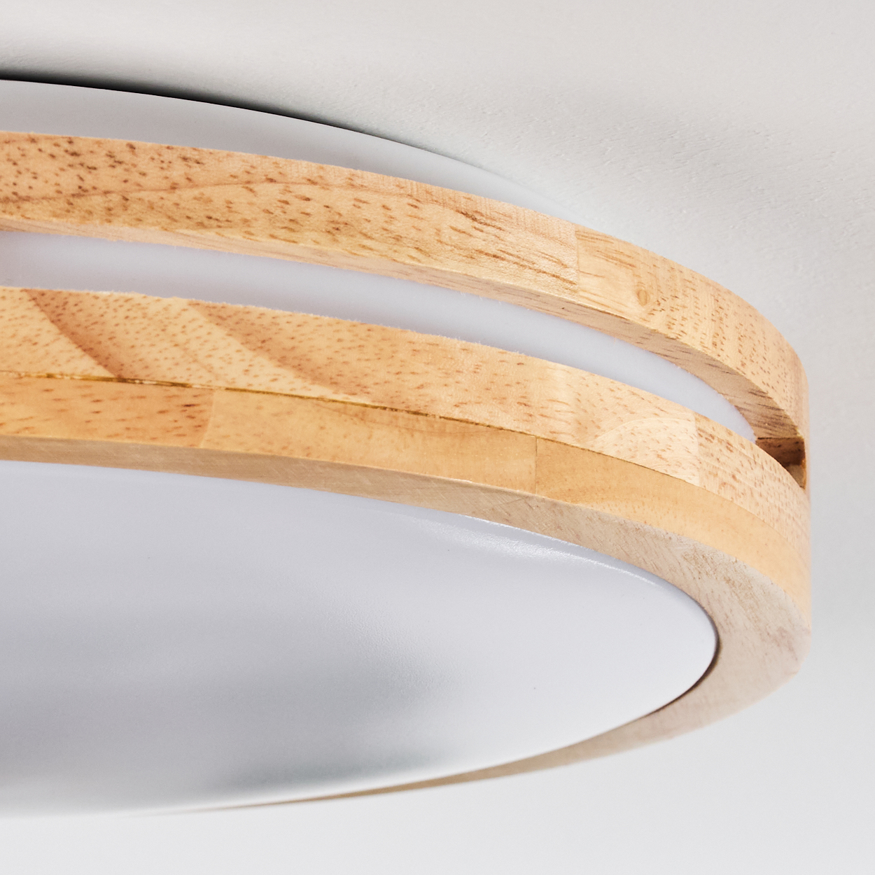 Nahaufnahme einer modernen Deckenlampe. Sie hat einen Holzrahmen mit weißem Licht und einem weißen Sockel. Der Hintergrund ist weiß.