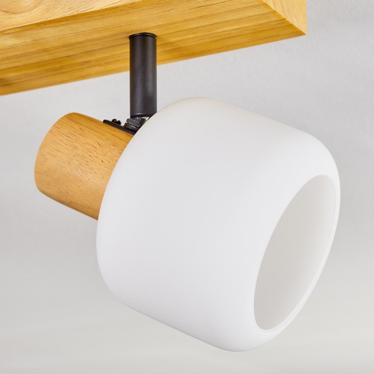 Eine moderne Deckenlampe mit weißem, zylindrischem Schirm, Holzakzenten und einer schwarzen Metallhalterung auf weißem Hintergrund.