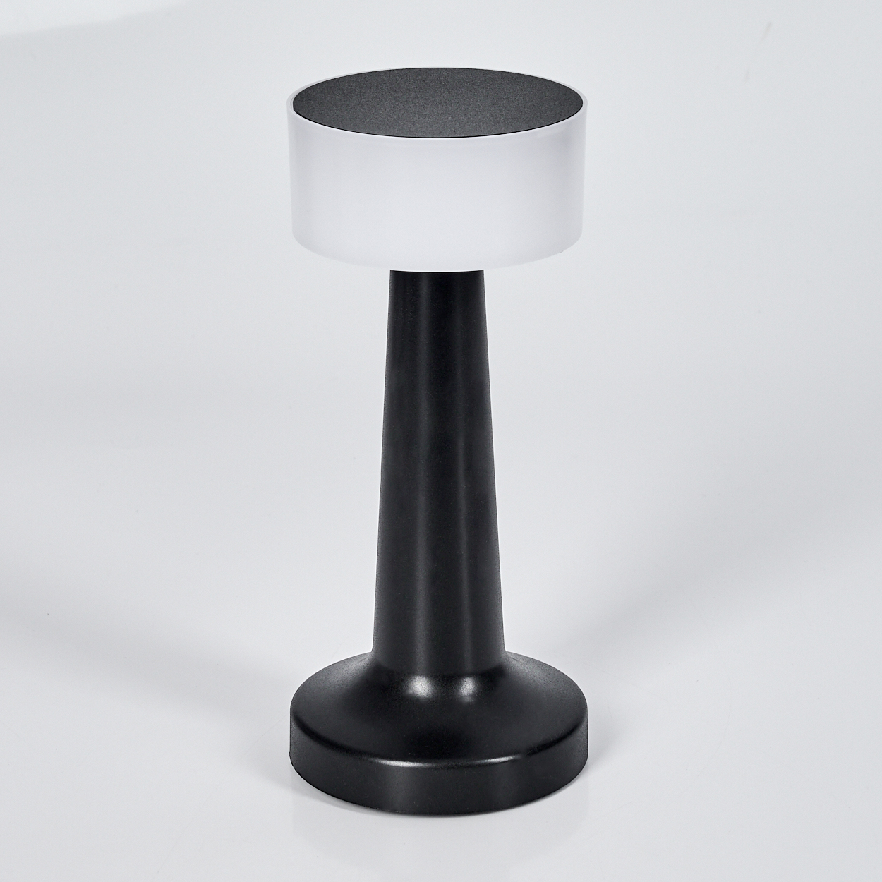 Eine moderne Tischlampe mit schwarzem Fuß und Stiel, weißem Mittelteil und dunkelgrauer Oberseite. Der Hintergrund ist weiß.