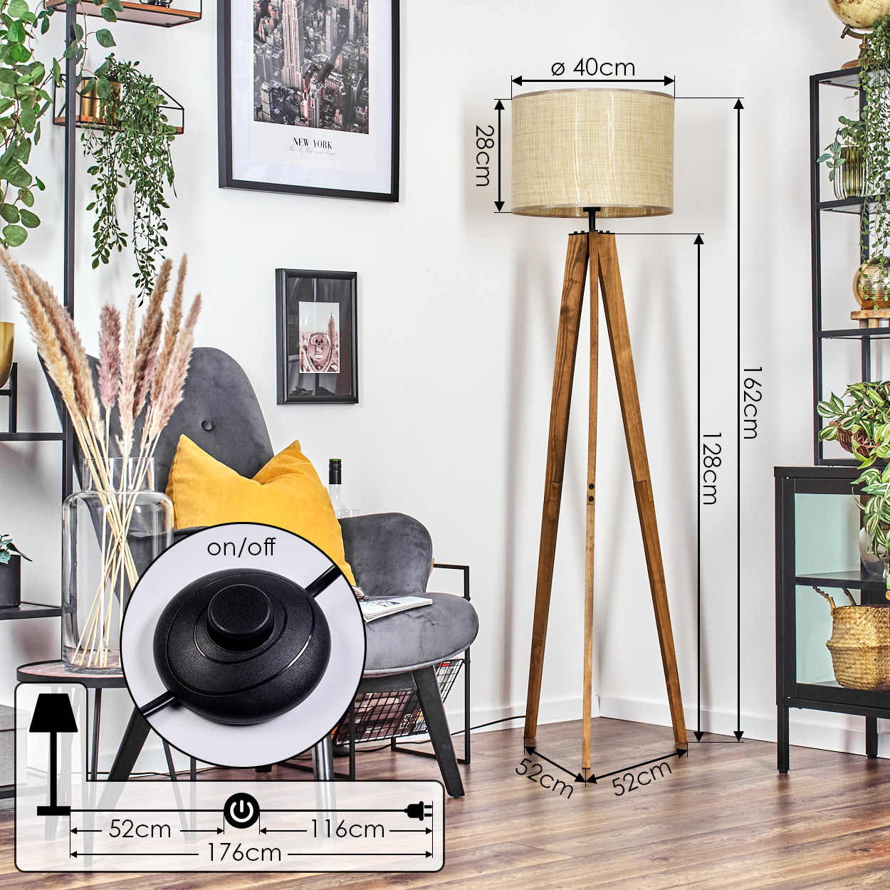 Ein stilvolles Zimmer mit einer hölzernen Stativ-Stehlampe, einem grauen Sessel und gerahmten Bildern an einer weißen Wand.
