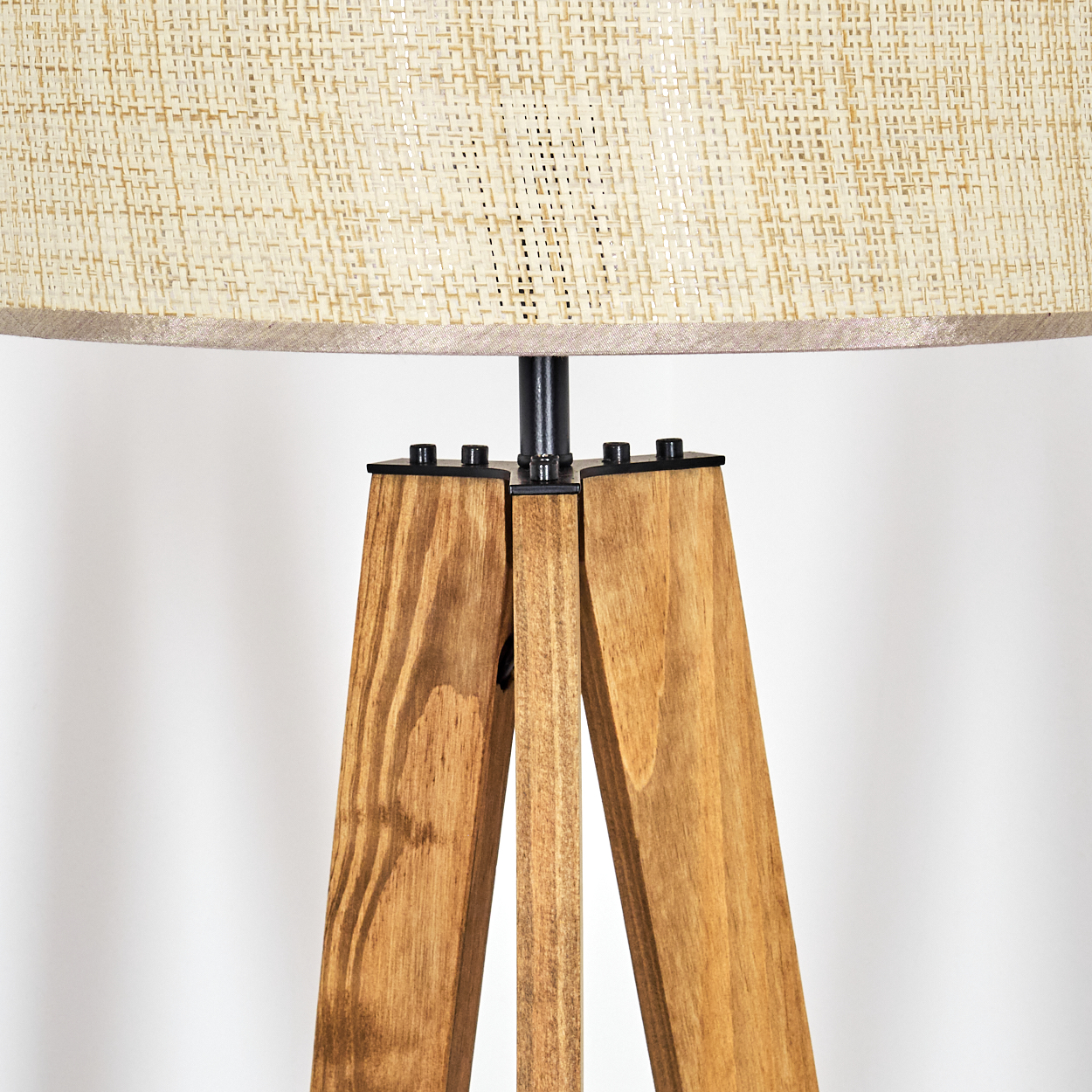 Eine Stehlampe mit Holzstativ und gewebtem Lampenschirm. Die Lampe hat einen hellbraunen Schirm und einen Holzfuß. Der Hintergrund ist weiß.