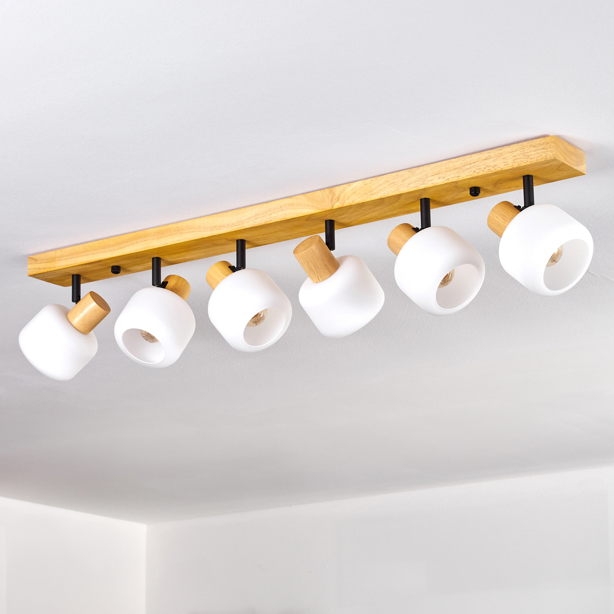 Deckenleuchte mit sechs weißen Lampen und Holzakzenten, montiert auf einem Holzbalken an einer weißen Decke.