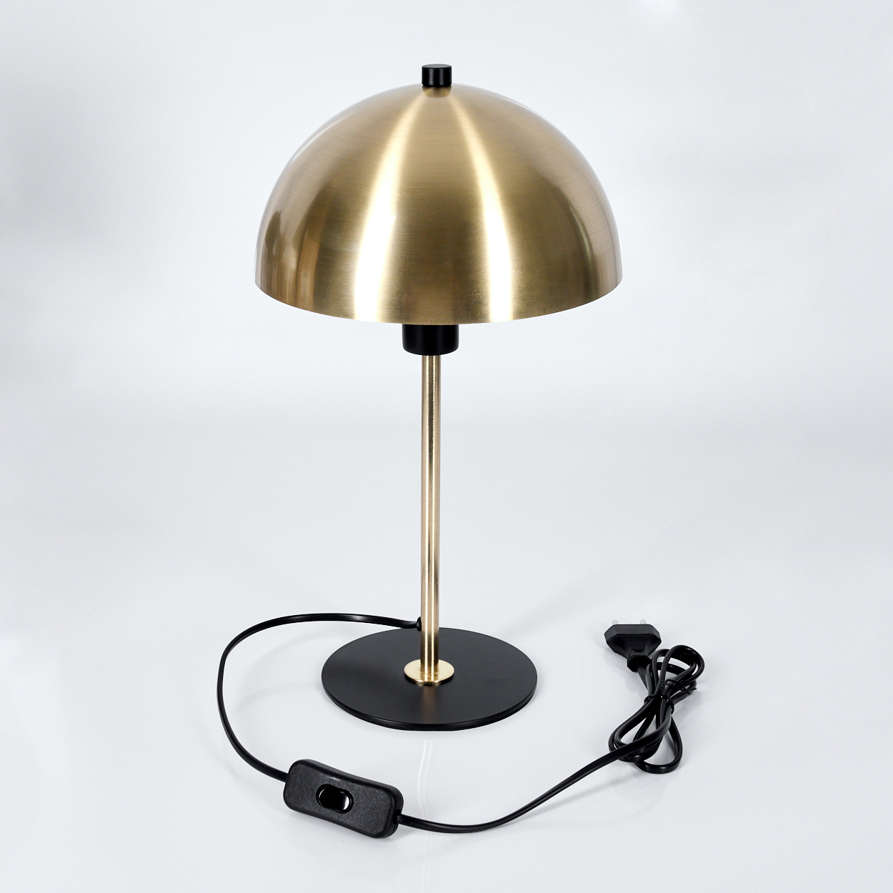 Eine messingfarbene Kuppellampe mit schwarzem Sockel und Stiel. Ein schwarzes Netzkabel mit Schalter und Stecker liegt darunter. Weißer Hintergrund.