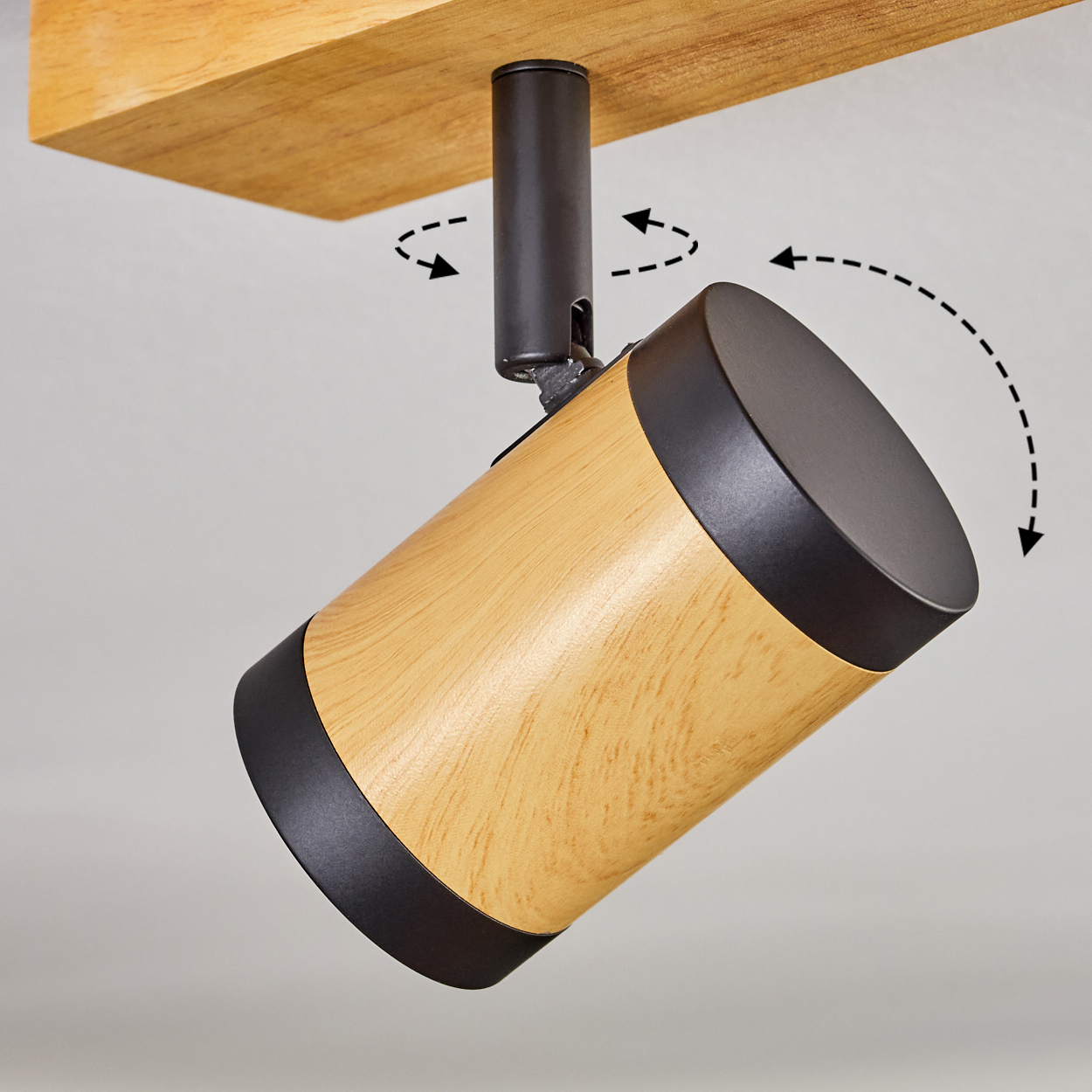 Ein Strahler mit Holzmaserung, schwarzen Rändern und einer schwarzen Stange. Die Lampe ist an einem Holzbalken befestigt. Pfeile zeigen die Bewegung an.