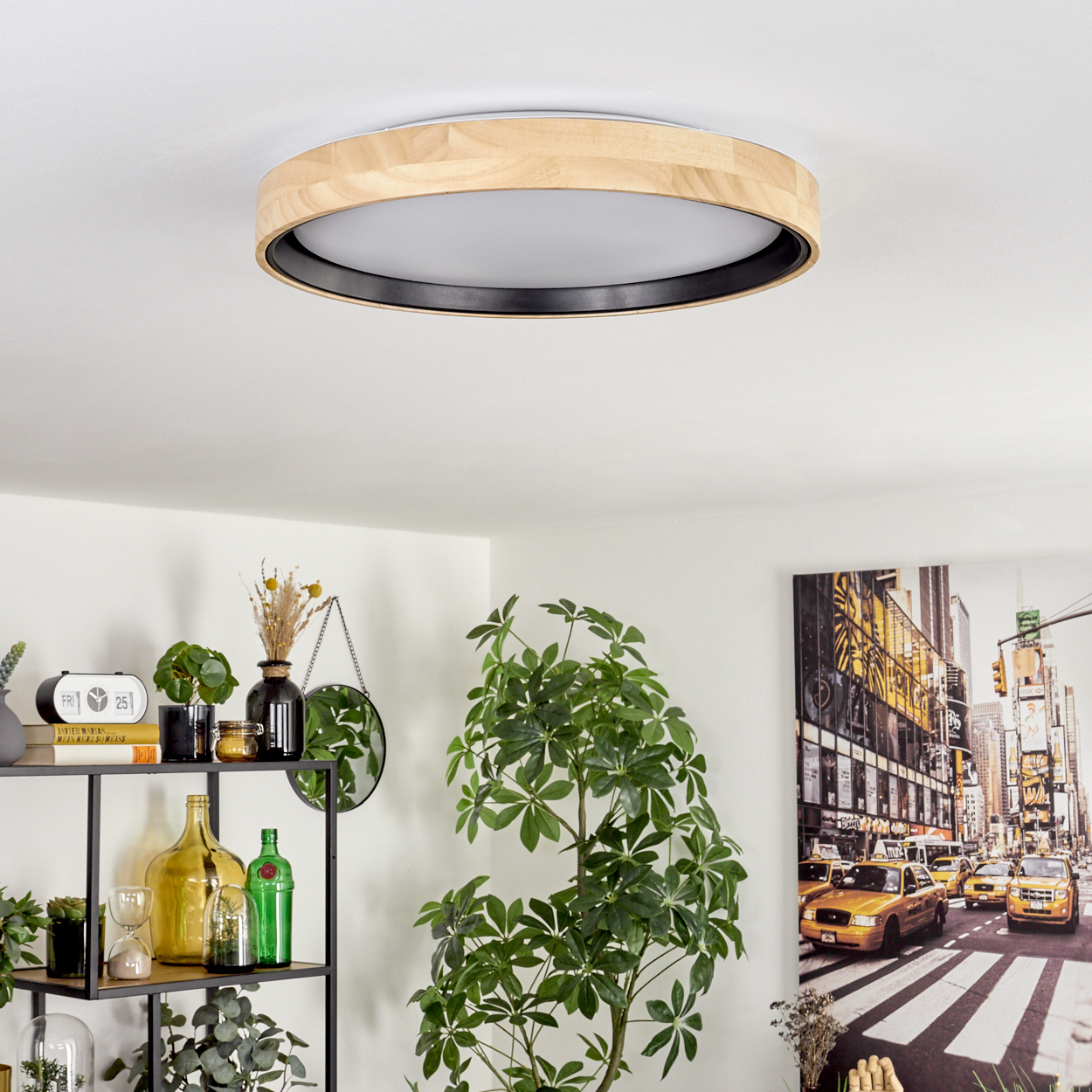 Eine Deckenlampe aus Holz und Schwarz. Darunter ein Regal mit Pflanzen und Flaschen. Ein Gemälde einer New Yorker Straßenszene hängt an der Wand.