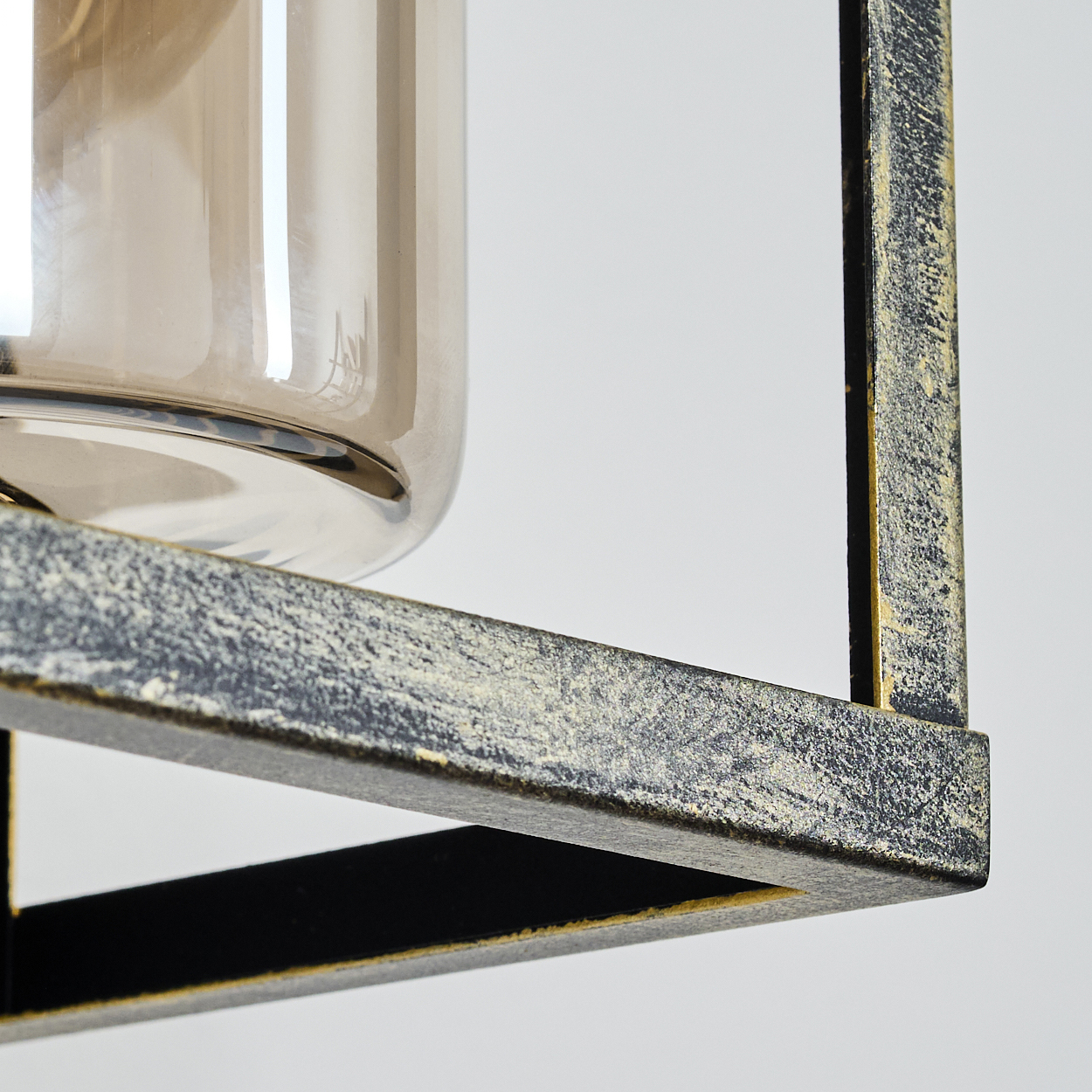 Nahaufnahme einer Lampe. Über einem Metallrahmen mit gelber und schwarzer Farbe befindet sich ein klares Glas. Der Hintergrund ist weiß.