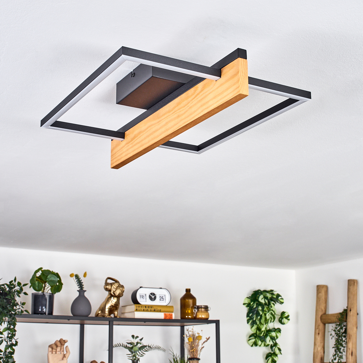 Moderne Deckenleuchte mit schwarzem und Holzrahmen. Darunter ein Regal mit Pflanzen, Dekoration und einer Holzleiter.