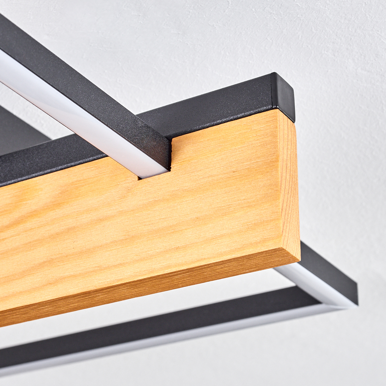 Nahaufnahme einer modernen Leuchte mit Holz- und schwarzem Metallrahmen. Weiße LED-Lichtstreifen sind sichtbar.