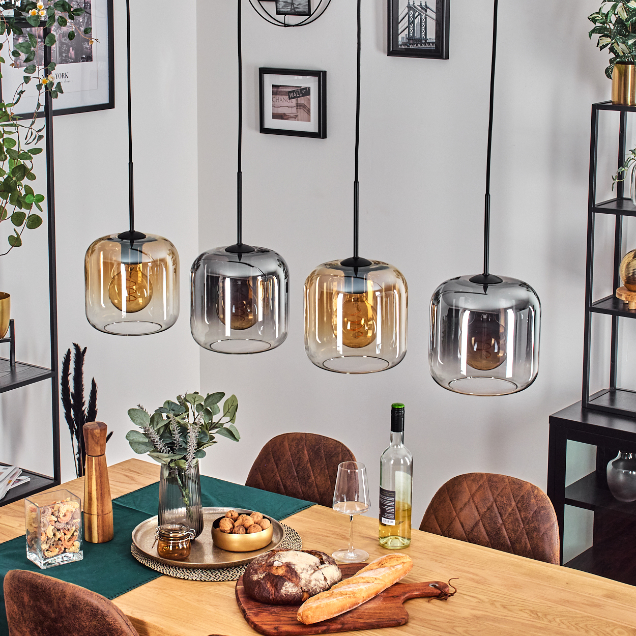 Esszimmer-Szene. Vier Pendelleuchten über einem Holztisch, der für eine Mahlzeit gedeckt ist. Brot, Wein und ein Mittelstück sind vorhanden.