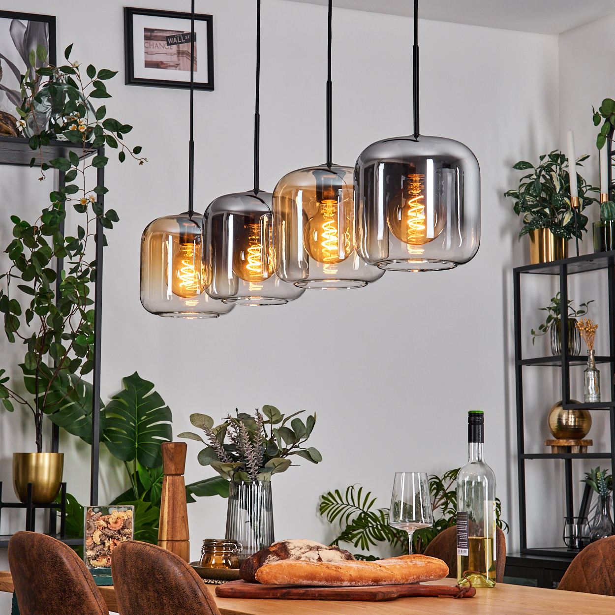 Esszimmer mit Hängelampen, Tisch für das Abendessen mit Brot, Wein und Grün eingerichtet. Lampen sind an.