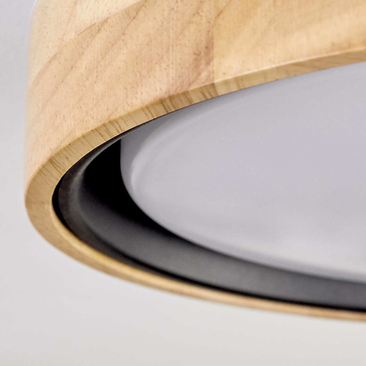 Nahaufnahme einer Holzlampe mit schwarzem Ring und weißem Lichtdiffusor. Der Hintergrund ist weiß.