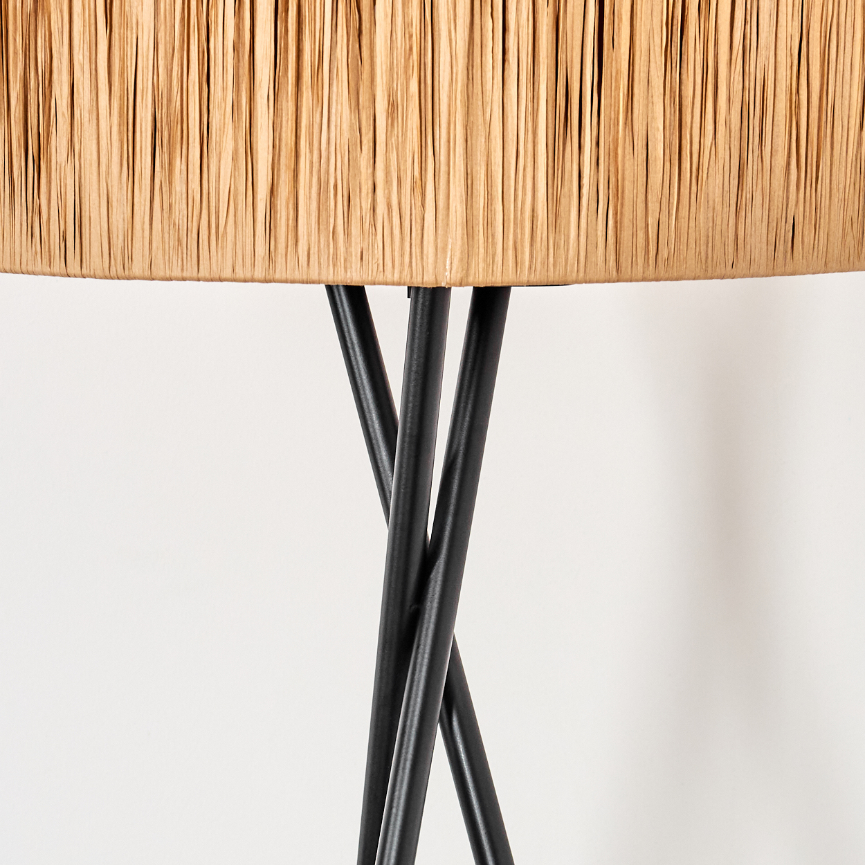 Nahaufnahme einer Lampe. Der Lampenschirm ist beige, die Beine sind schwarz. Der Hintergrund ist weiß.