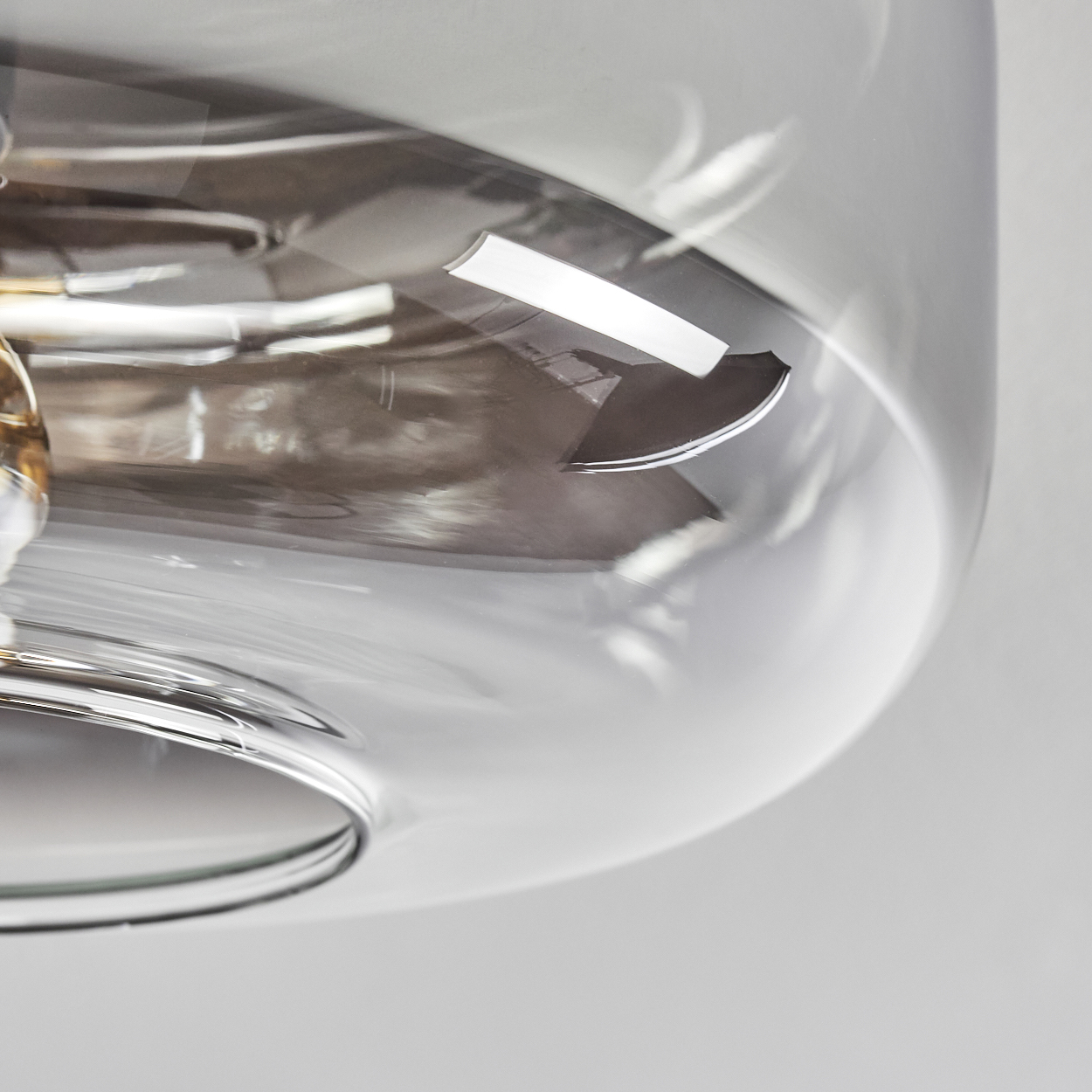 Nahaufnahme eines klaren, abgerundeten Glasschirmes. Das Glas reflektiert Licht und Umgebung, einige interne Armaturen sichtbar.