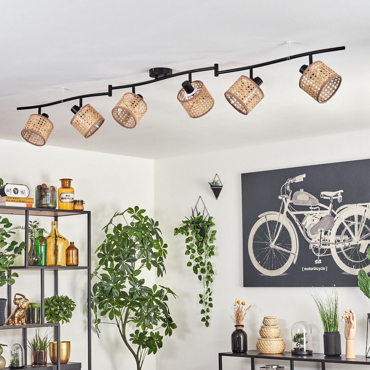 Deckenstrahler mit gewebten Schirmen. Ein dekoratives Regal mit Pflanzen und Flaschen. Ein Fahrrad-Kunstwerk und verschiedene Dekorationen sind sichtbar.