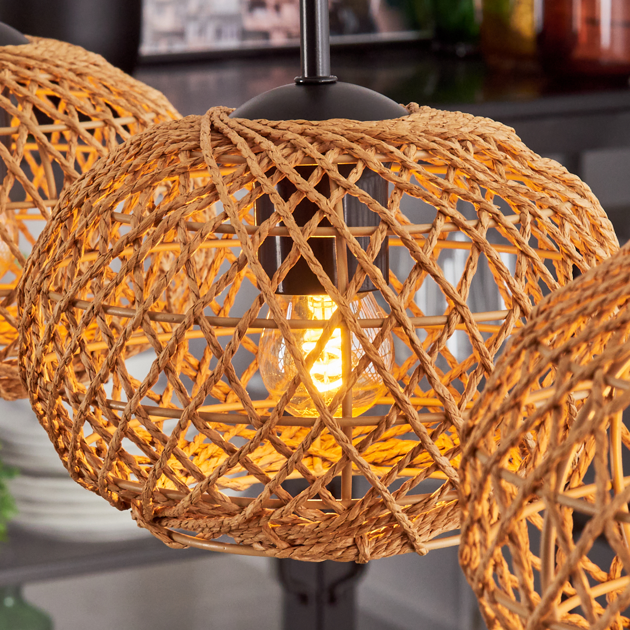 Nahaufnahme von geflochtenen Rattan-Leuchten mit glühenden Glühbirnen. Die Leuchten haben eine natürliche Farbe und hängen von der Decke.