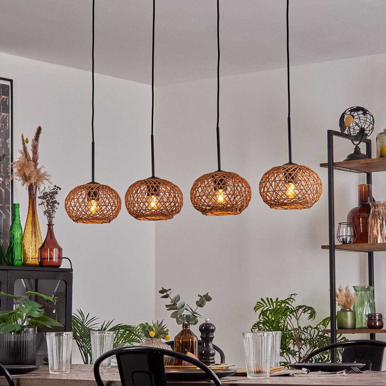 Esszimmer mit vier gewebten Pendelleuchten. Tisch mit Gläsern, Pflanzen und Dekoration. Regale mit Gegenständen im Hintergrund.