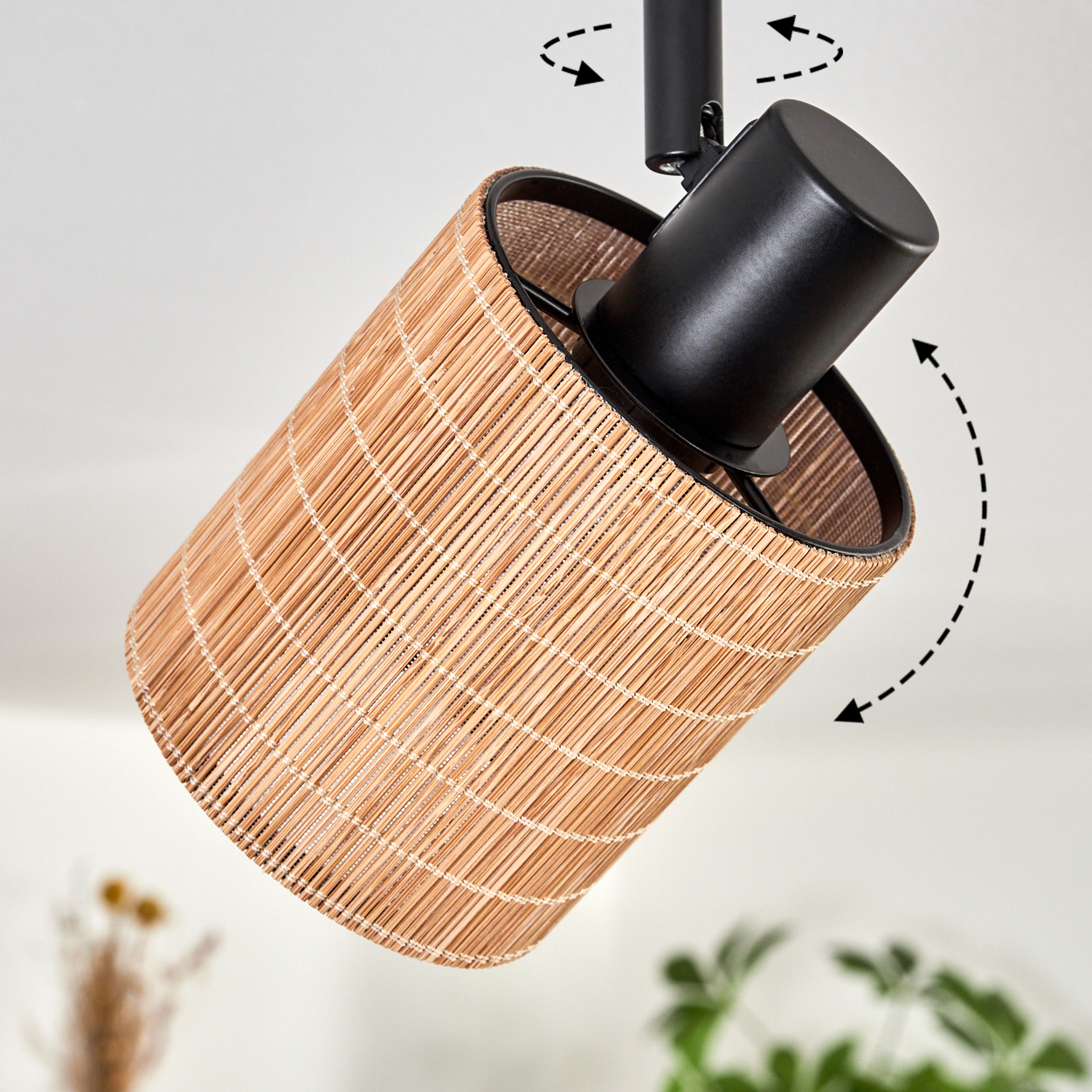 Lampenschirm aus Bambus mit schwarzem Metallgestell. Der Schirm ist zylindrisch, hellbraun. Pfeile zeigen die verstellbare Richtung der Lampe an.