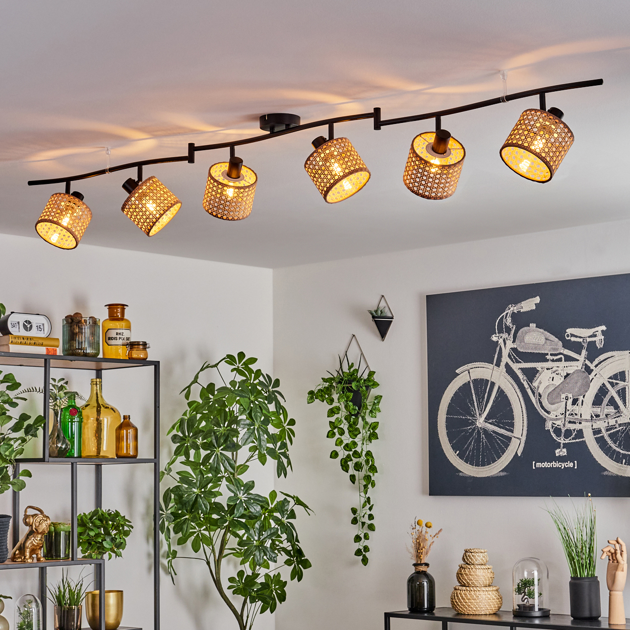Deckenleuchten mit gewebten Schirmen beleuchten einen Raum. Pflanzen und Dekorationen schmücken den Raum, mit einem Fahrradkunstwerk an der Wand.
