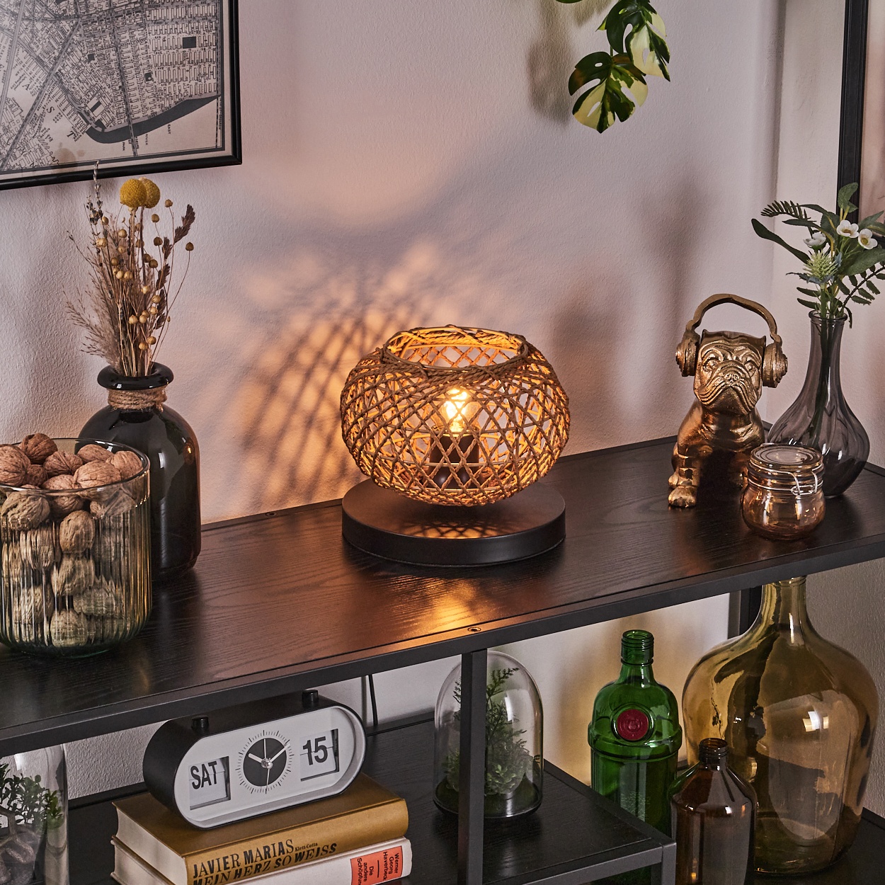 Ein Regal zeigt eine Lampe, Vasen, eine Uhr und andere Dekorationen. Die Lampe hat einen gewebten Schirm, und eine Bulldoggenstatue mit Kopfhörern ist zu sehen.
