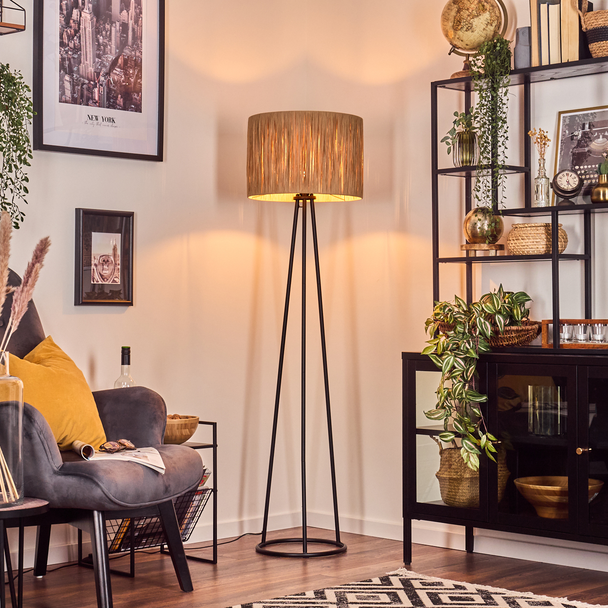 Ein Wohnzimmer mit Stehlampe, Sessel und schwarzem Regal mit verschiedenen Dekorationen und Pflanzen.