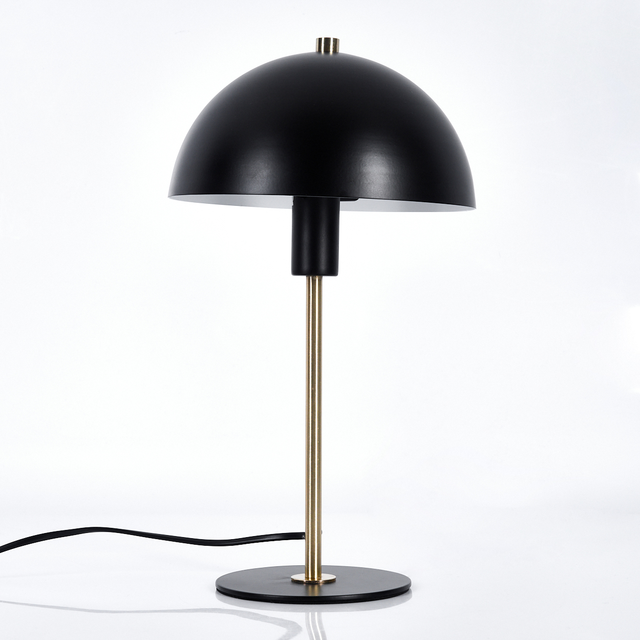Eine moderne schwarz-goldene Schreibtischlampe. Sie hat einen kuppelförmigen Schirm, einen goldenen Stiel und einen schwarzen Sockel. Ein schwarzes Kabel ist angebracht.