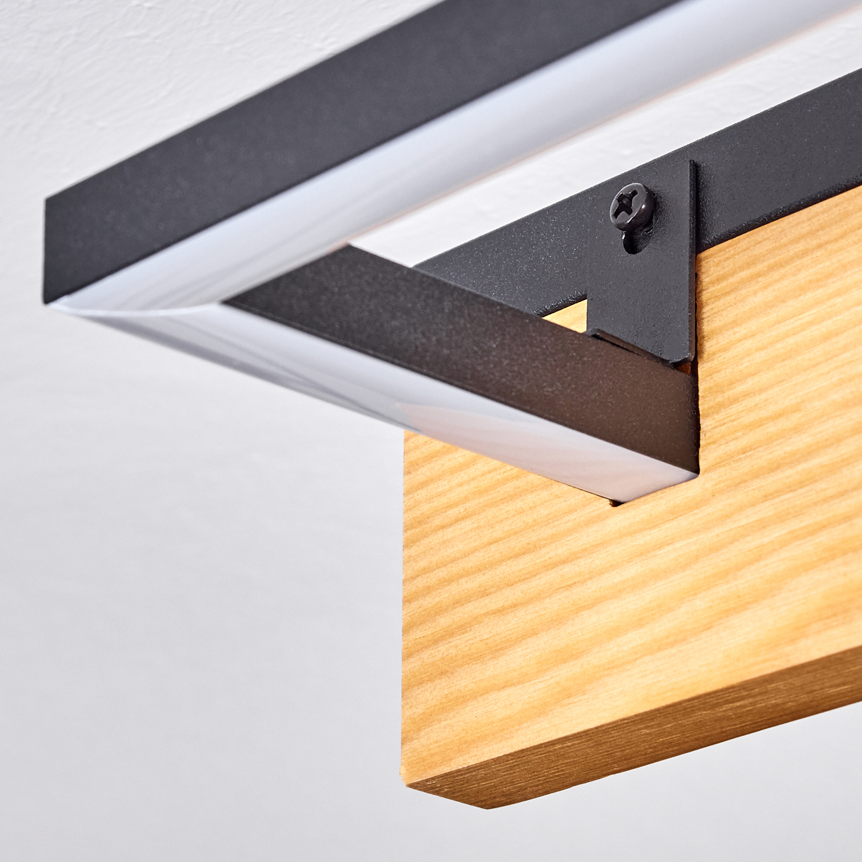 Nahaufnahme eines Holzbalkens, der an einem schwarzen Metallrahmen befestigt ist. Ein weißer Lichtstreifen verläuft entlang des Rahmens.