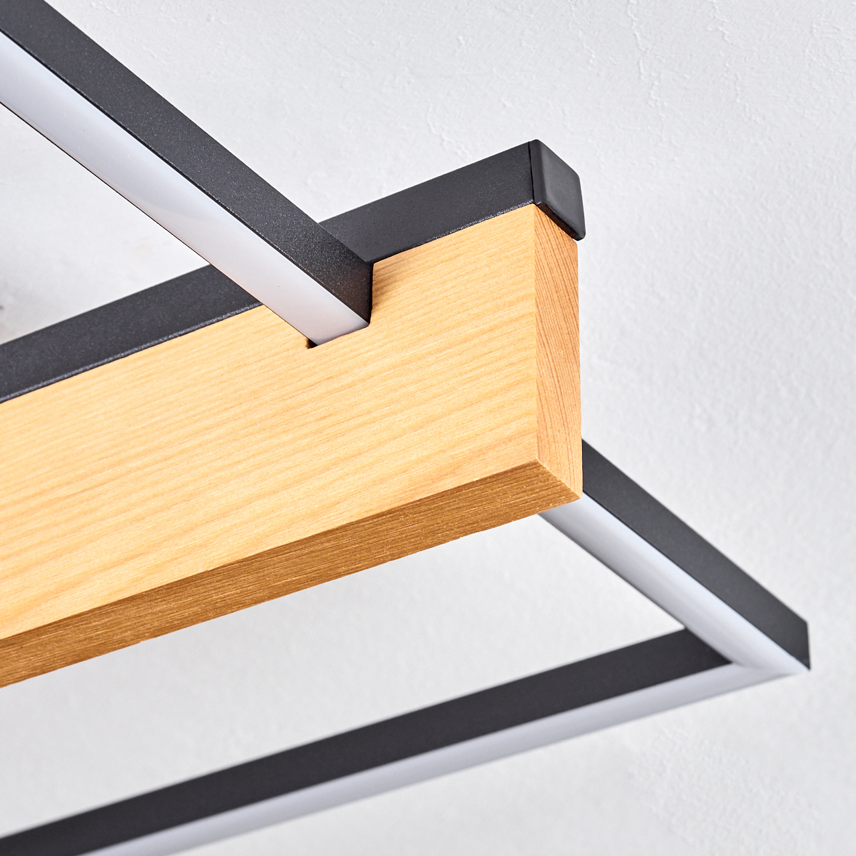 Nahaufnahme einer modernen Leuchte. Sie hat einen Holzbalken, einen schwarzen Metallrahmen und integrierte weiße LED-Beleuchtung.