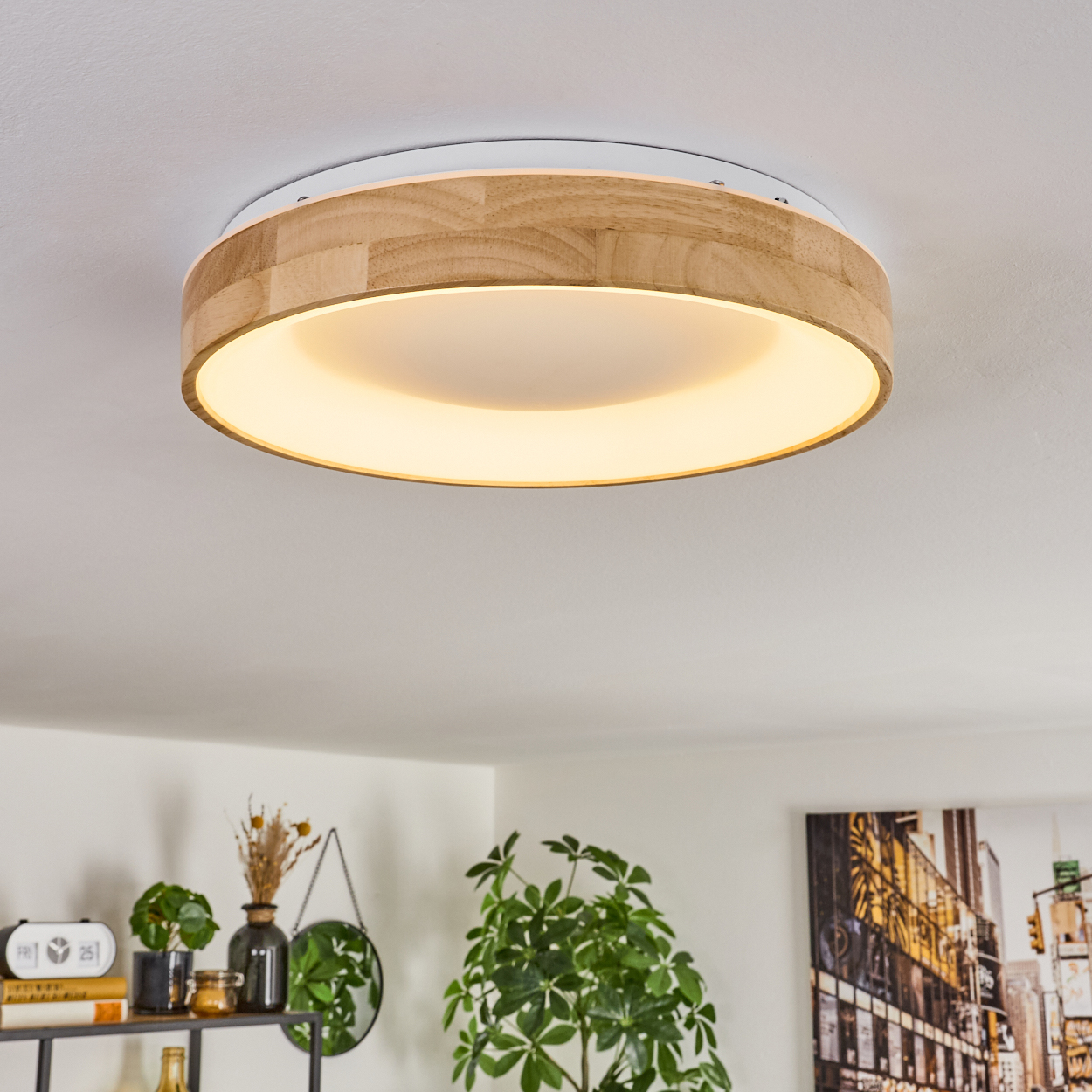 Eine Holz- und weiße Deckenlampe mit hellem Innenlicht. Darunter ist ein Regal mit Pflanzen und Dekoration zu sehen.